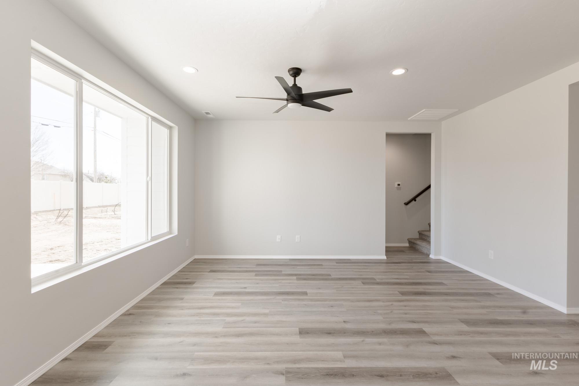 Empty room featuring light wood-style flooring, a ceiling fan, stairs, and recessed lighting