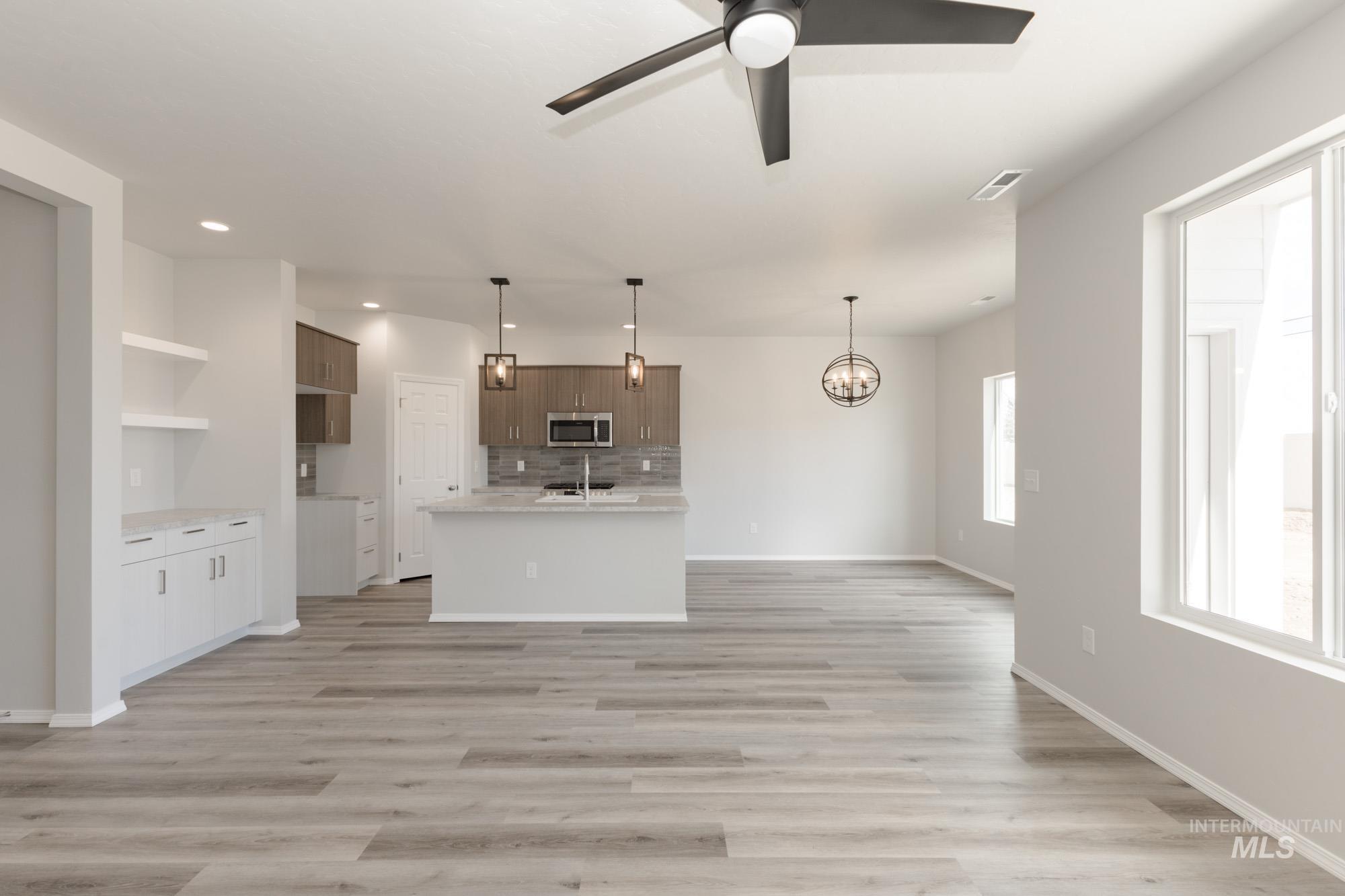 Unfurnished living room featuring light wood finished floors, a chandelier, ceiling fan, and recessed lighting