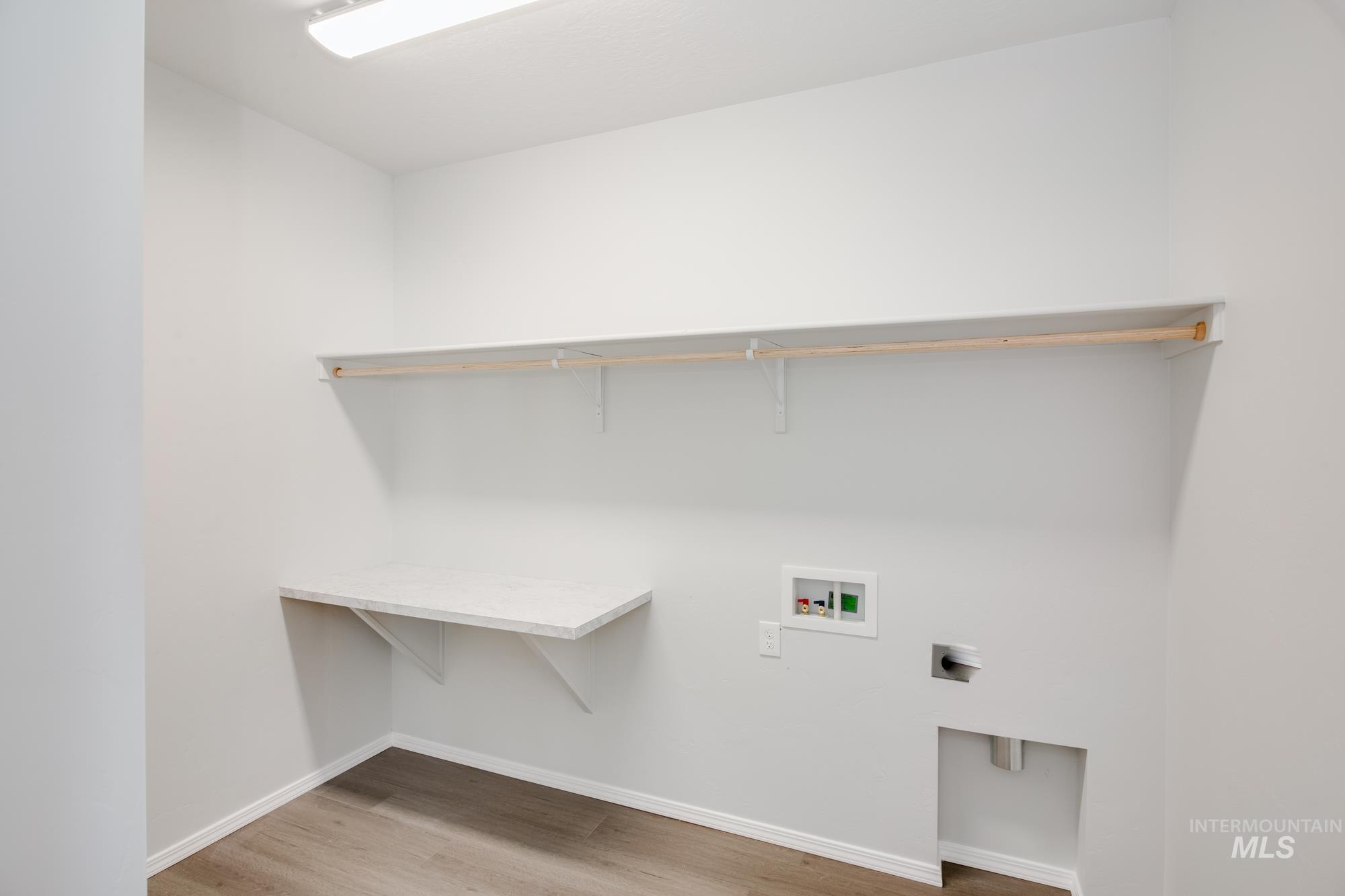 Laundry room with hookup for a washing machine, light wood finished floors, and hookup for an electric dryer