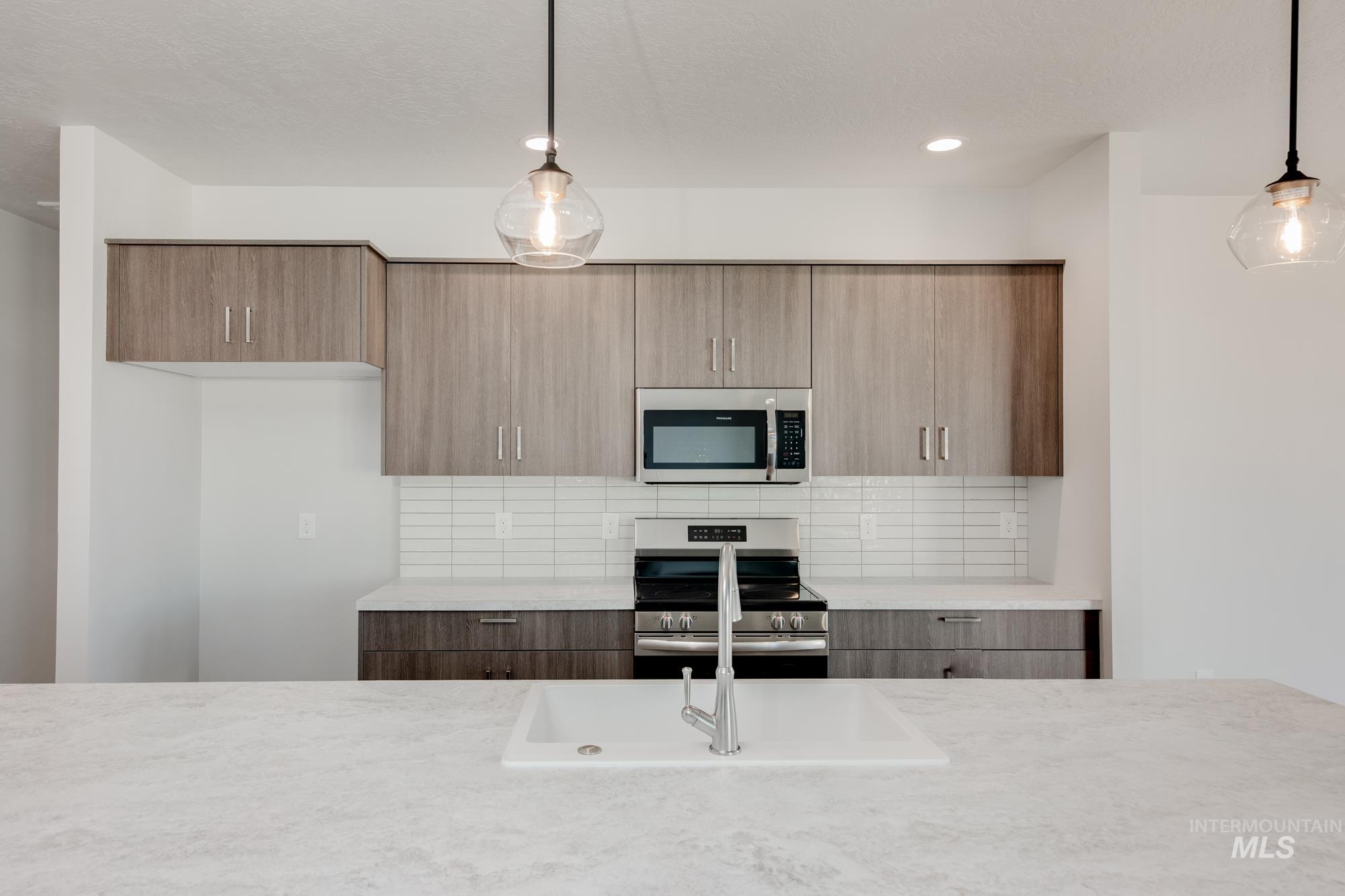 Kitchen featuring modern cabinets, appliances with stainless steel finishes, decorative backsplash, pendant lighting, and recessed lighting
