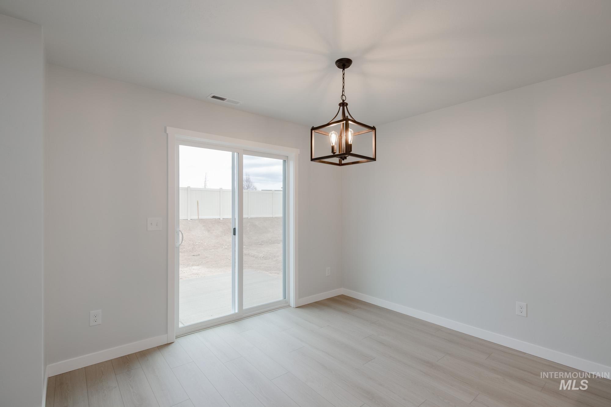 Spare room featuring light wood-type flooring and a chandelier