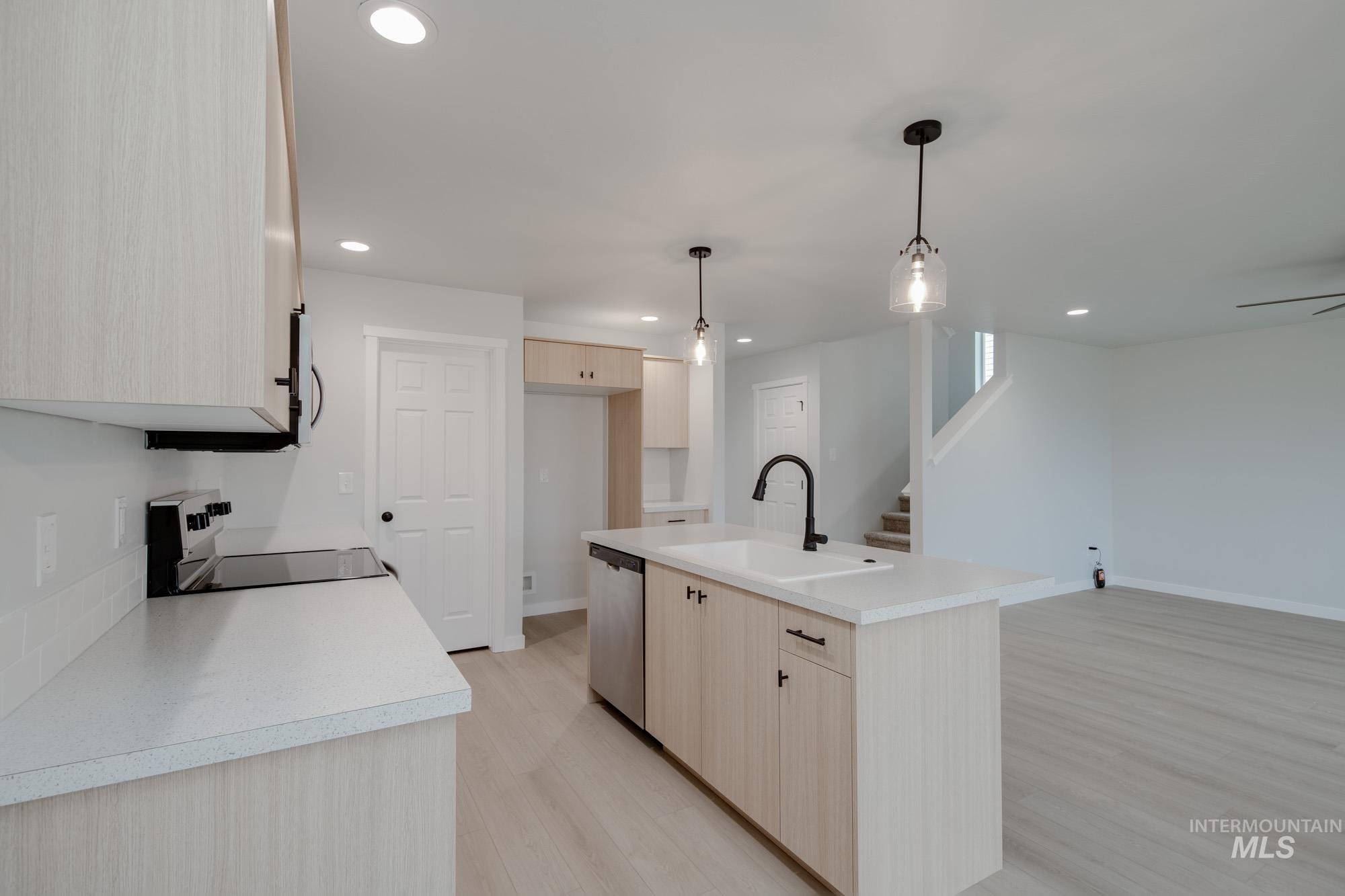 Kitchen featuring light brown cabinets, black range with electric cooktop, light countertops, light wood-style floors, and recessed lighting