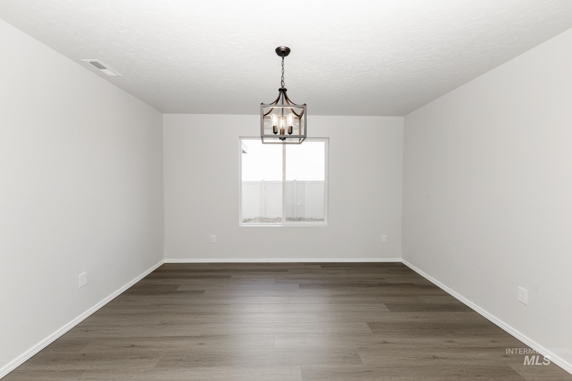 Unfurnished room with wood finished floors and a chandelier
