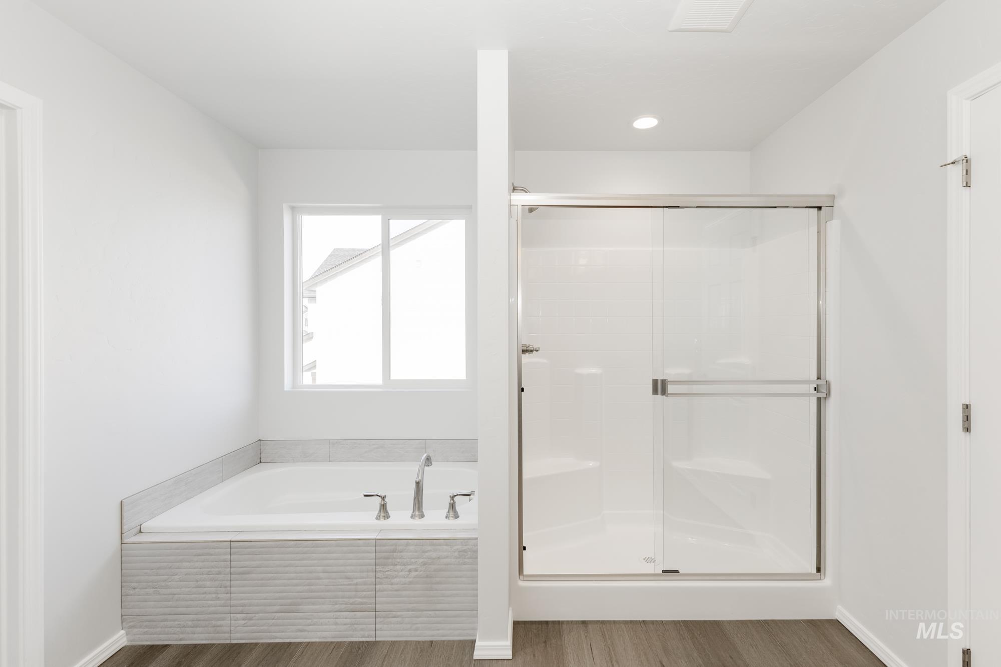 Full bath featuring a garden tub, wood finished floors, and a stall shower