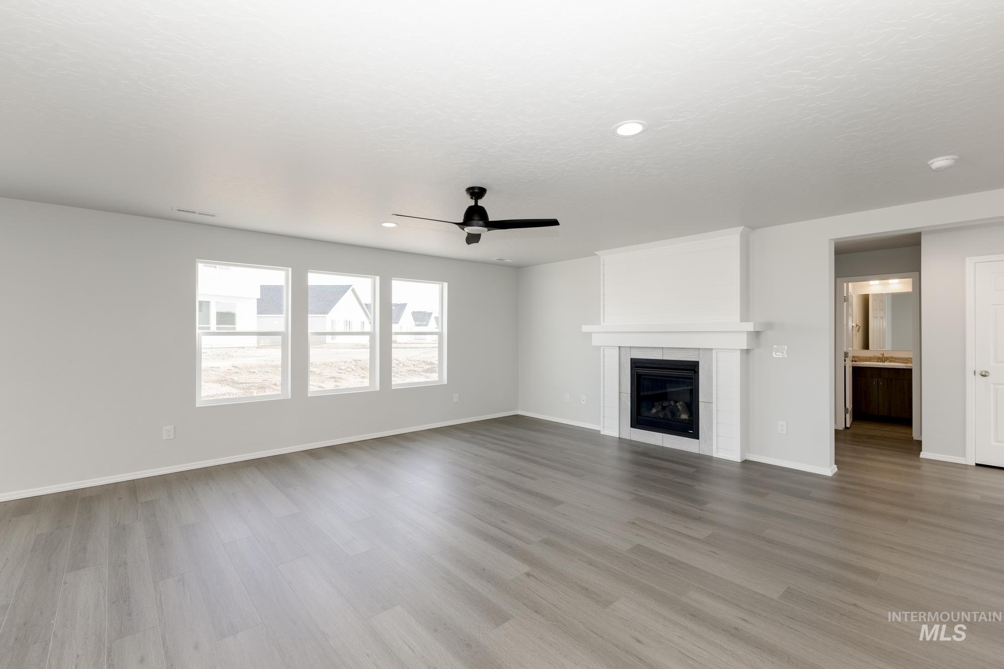 Unfurnished living room with a fireplace, ceiling fan, light wood-style floors, and recessed lighting