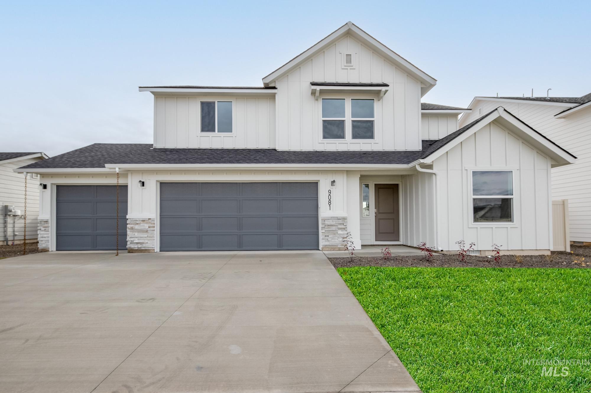 Modern farmhouse with board and batten siding, a front yard, a shingled roof, driveway, and an attached garage
