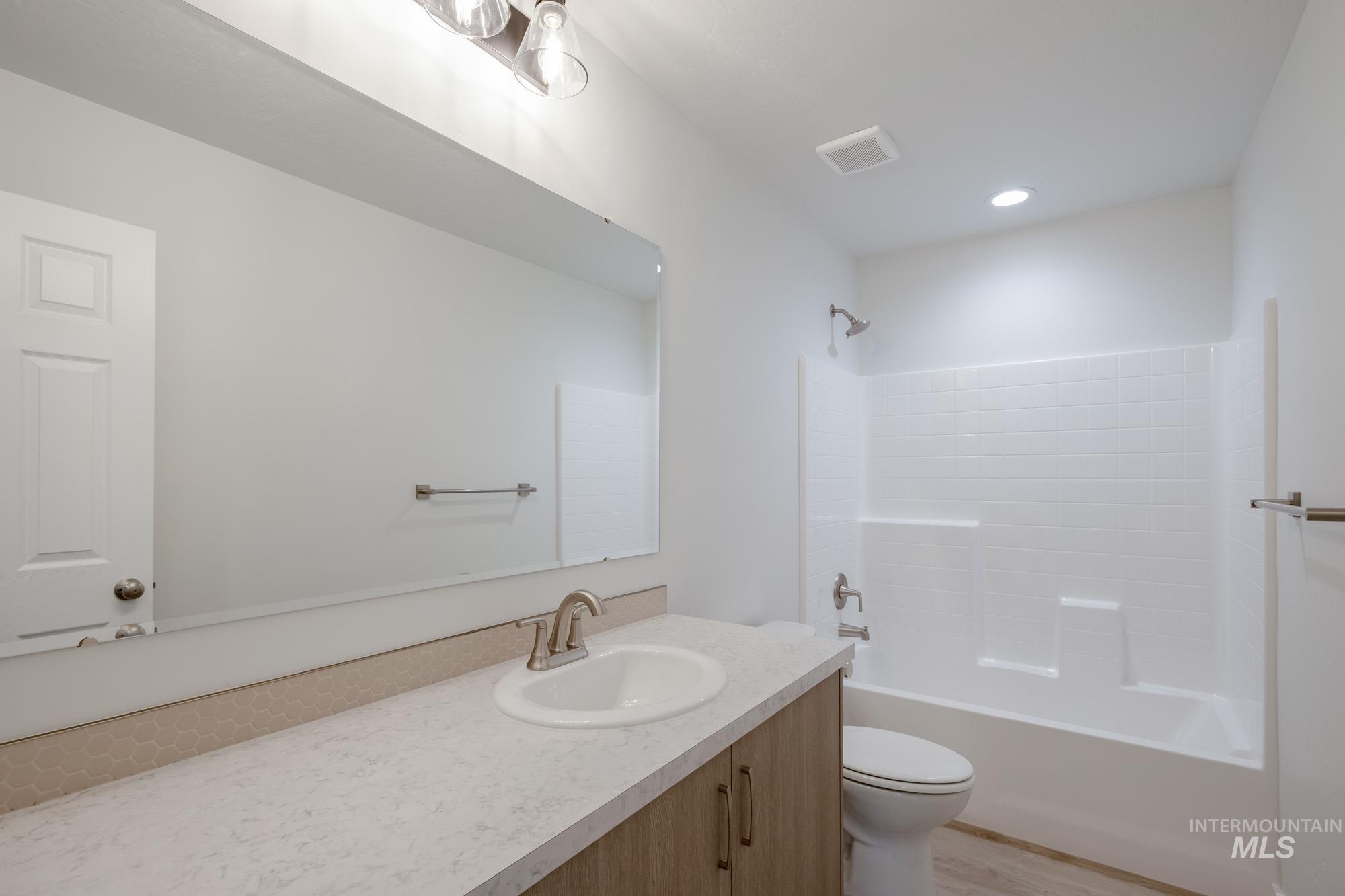 Bathroom with vanity,  shower combination, light wood-style flooring, and recessed lighting