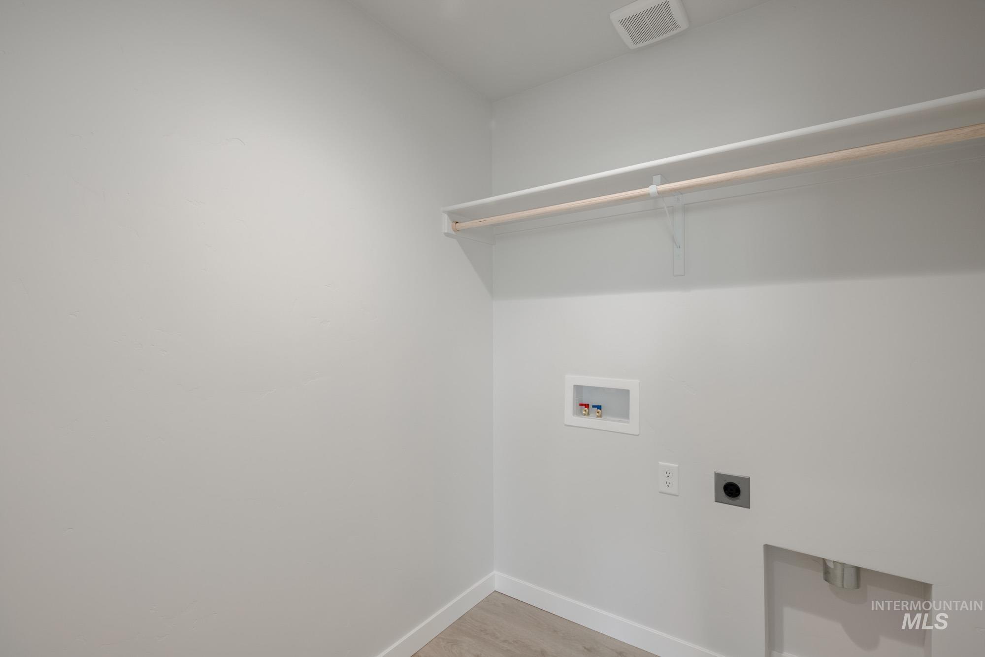Laundry room with hookup for an electric dryer, light wood-style floors, and hookup for a washing machine