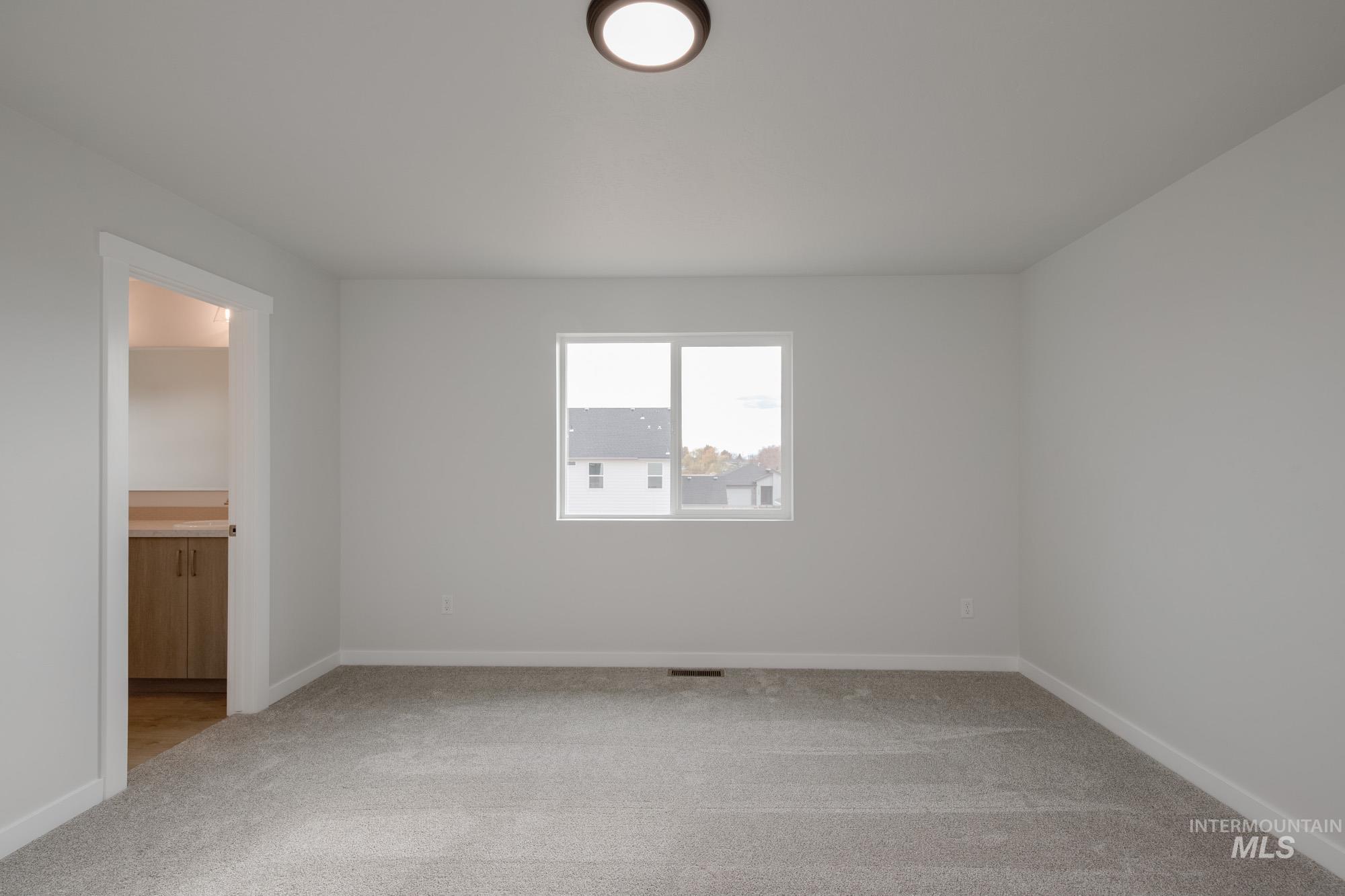 Unfurnished bedroom featuring light colored carpet and connected bathroom