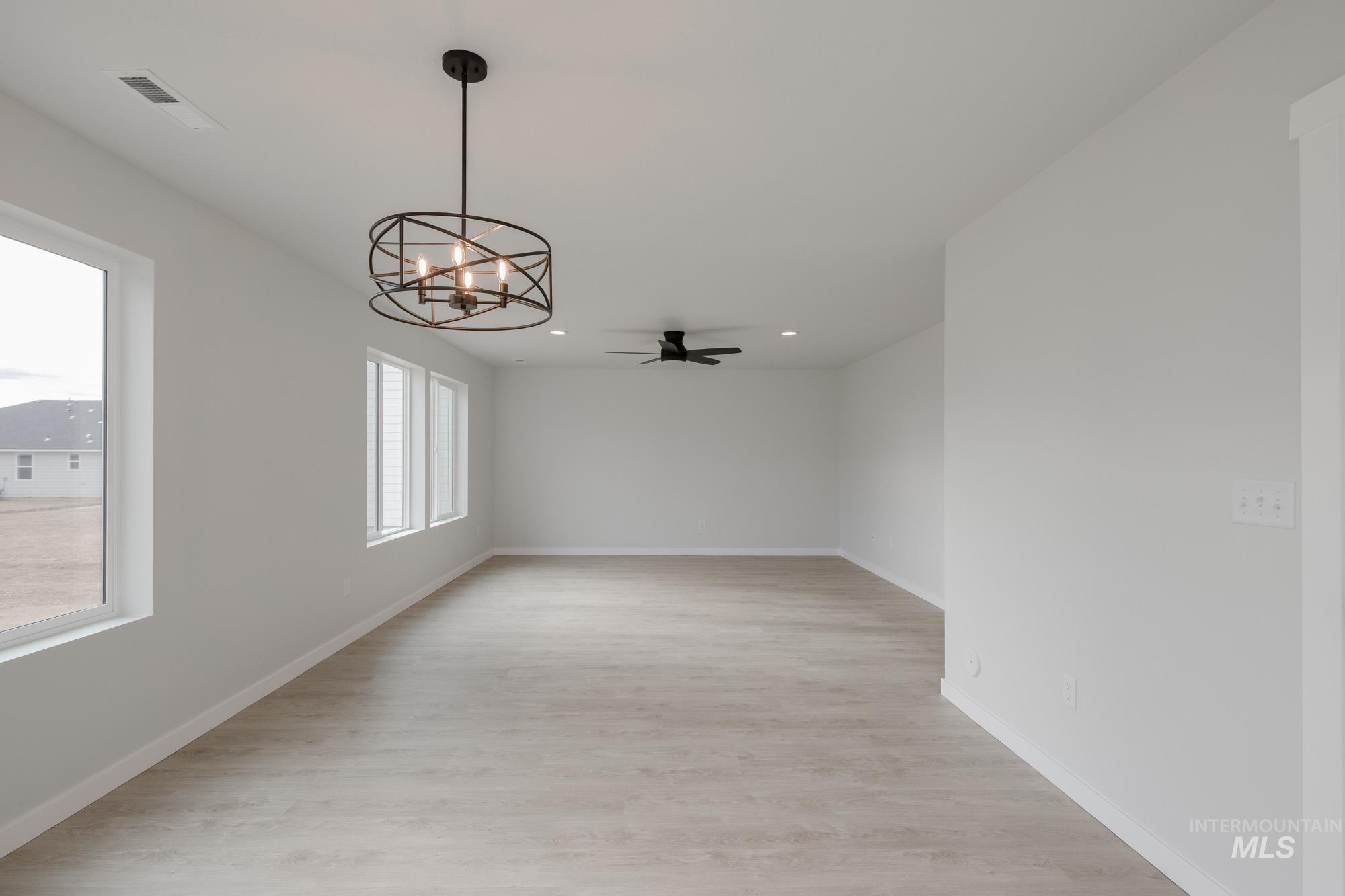 Unfurnished dining area with a chandelier, light wood finished floors, a ceiling fan, and recessed lighting