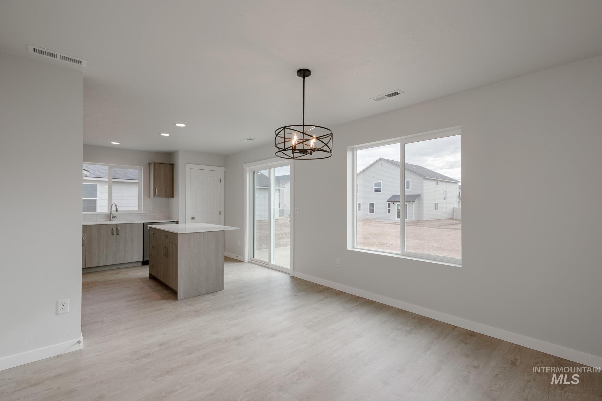 Kitchen featuring decorative light fixtures, a center island, light countertops, light wood finished floors, and a chandelier