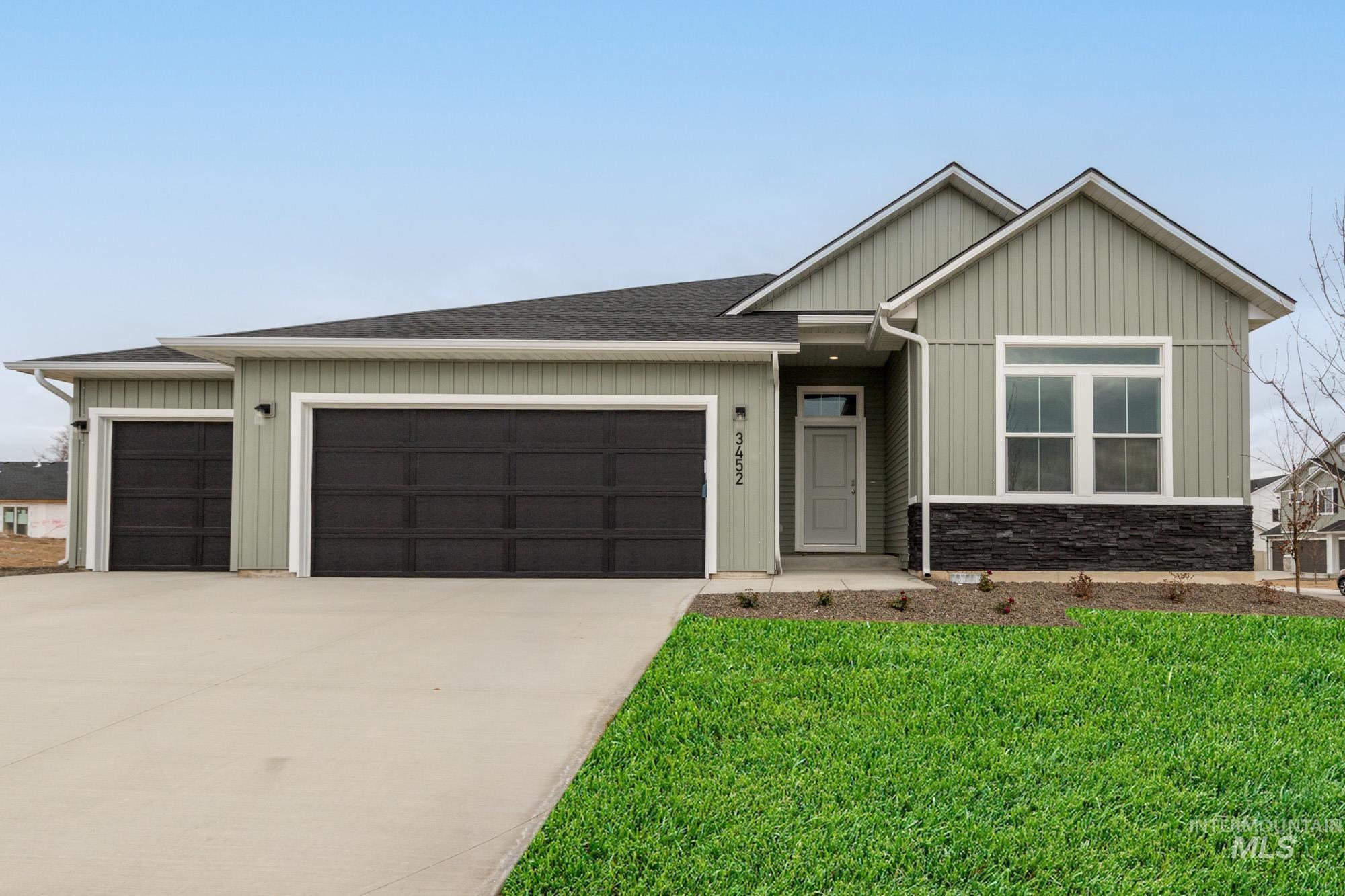 View of front of home with board and batten siding, concrete driveway, a garage, a front yard, and a shingled roof