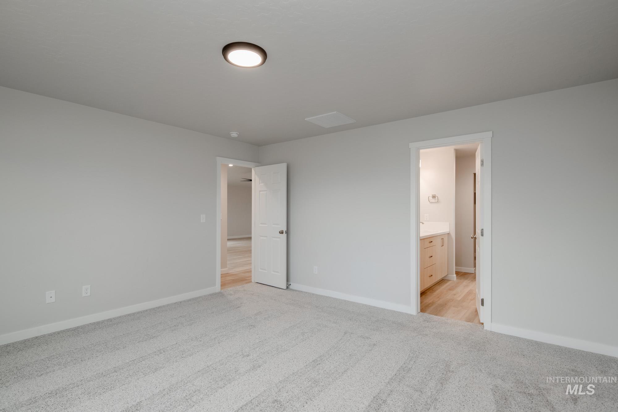 Unfurnished bedroom with light carpet and connected bathroom