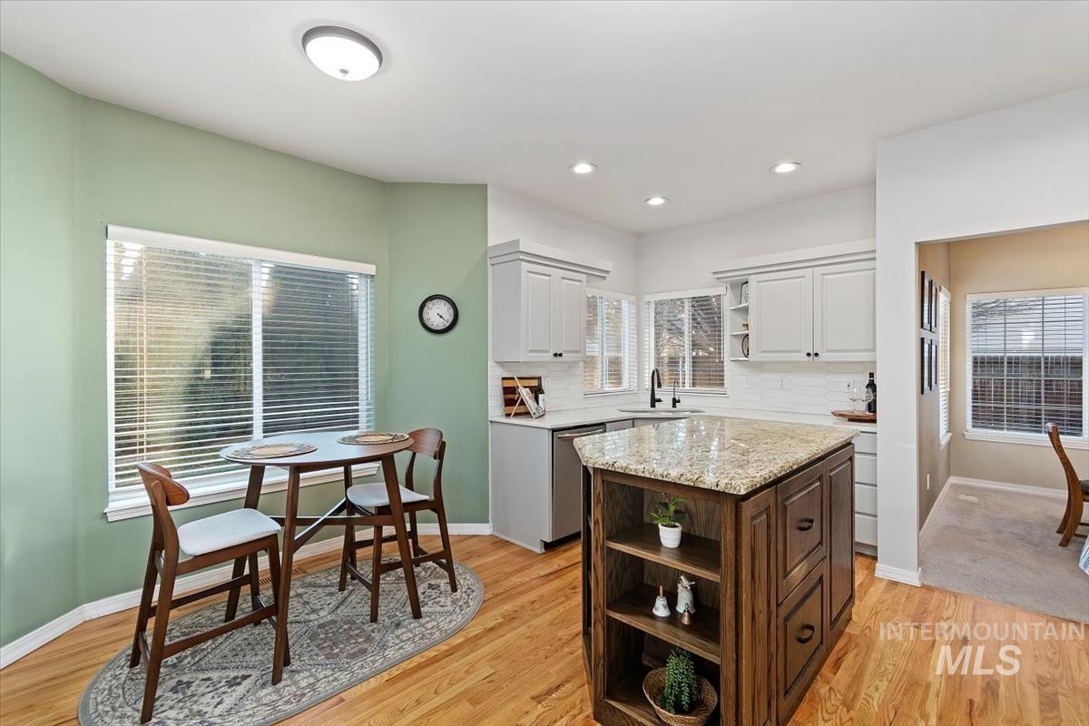 Kitchen featuring open shelves, light stone counters, stainless steel dishwasher, light wood finished floors, and white cabinetry