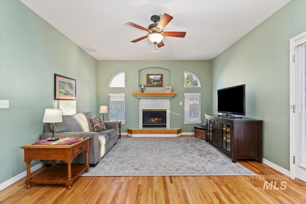 Living area featuring a fireplace, light wood-style flooring, and ceiling fan