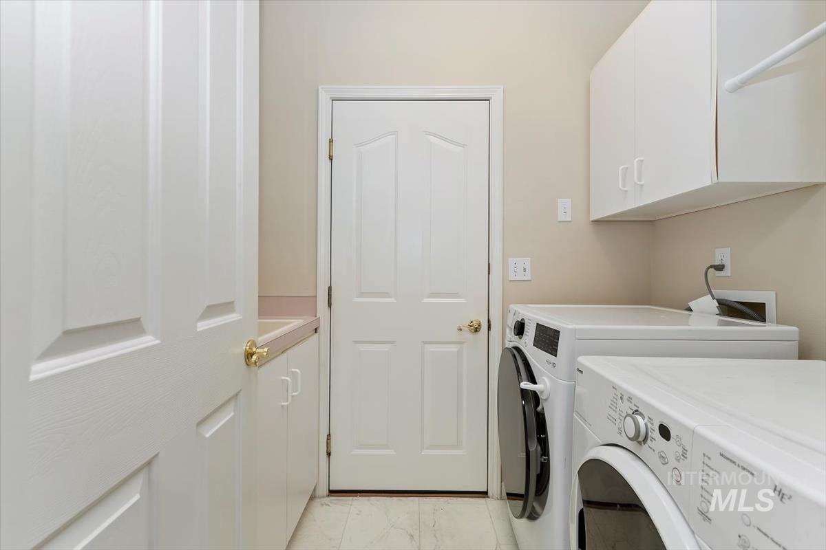 Washroom featuring light marble finish floors, cabinet space, and washer and clothes dryer