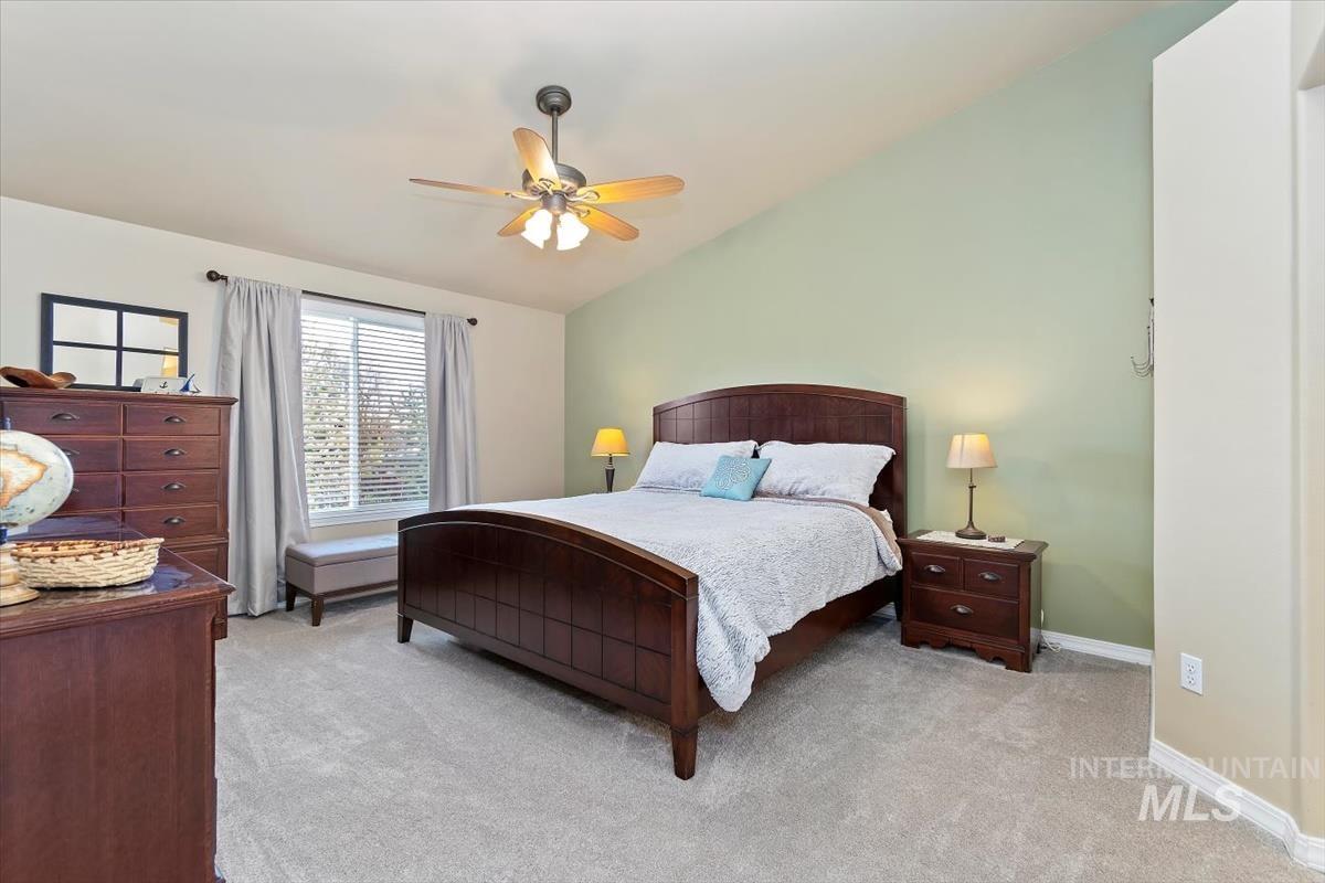 Bedroom featuring light colored carpet, lofted ceiling, and a ceiling fan
