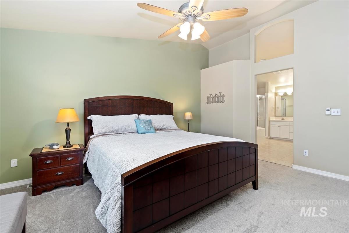 Bedroom with lofted ceiling, carpet flooring, ensuite bath, and ceiling fan