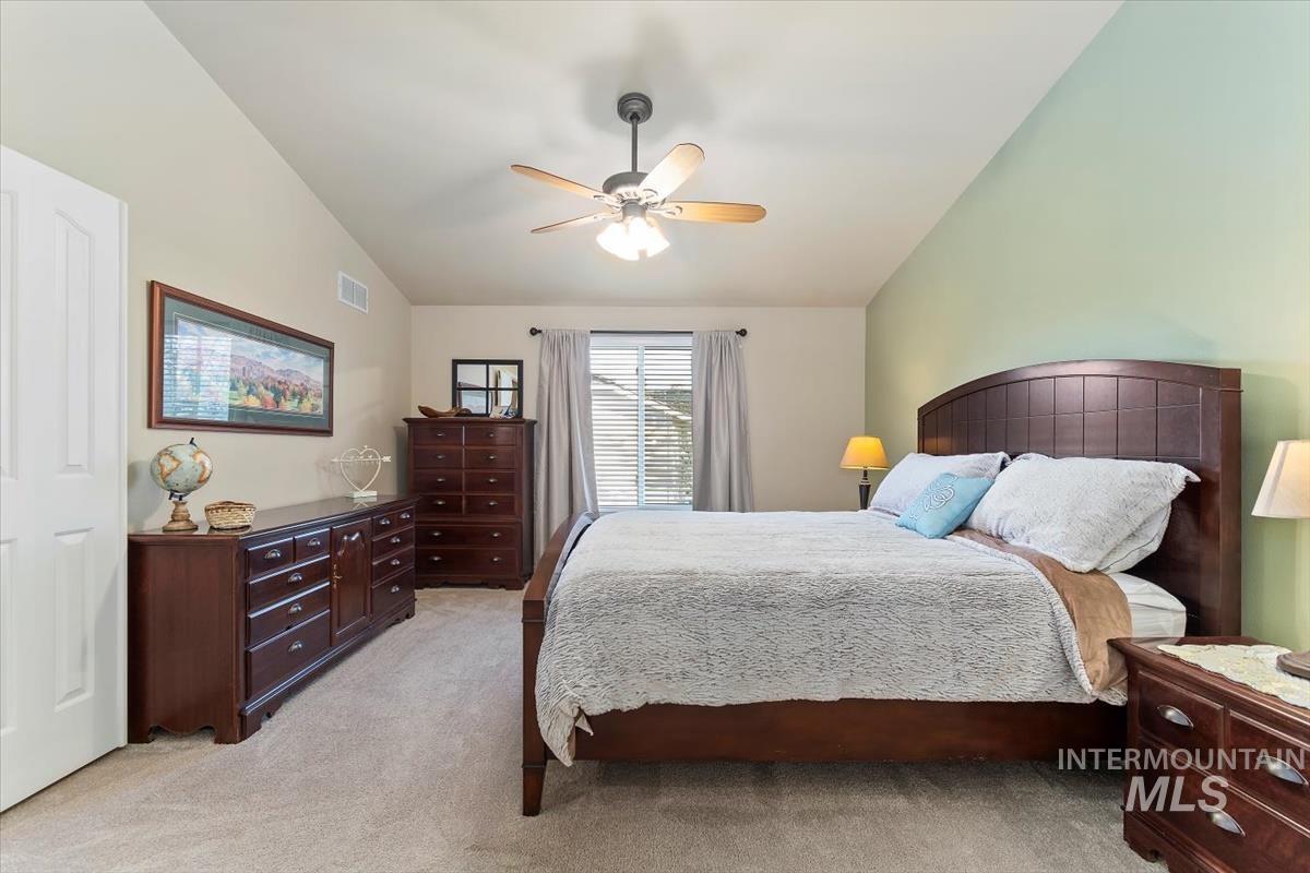 Bedroom featuring light colored carpet, lofted ceiling, and a ceiling fan