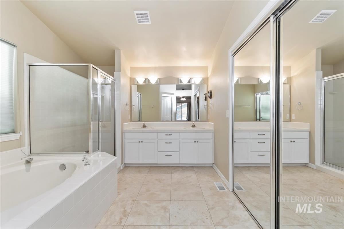 Full bathroom with double vanity, a garden tub, a shower stall, and light tile patterned flooring