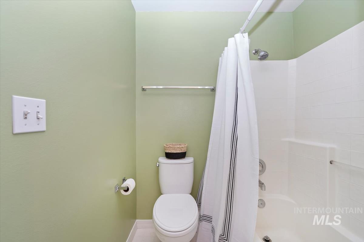 Full bath featuring toilet and shower / bath combination with curtain