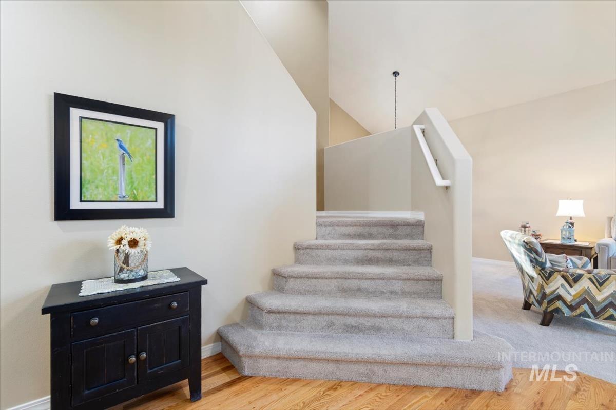 Stairs with wood finished floors and a towering ceiling
