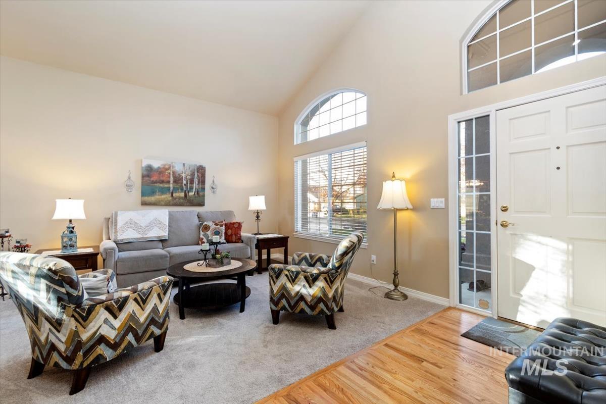 Living area with high vaulted ceiling, light wood-type flooring, and light colored carpet