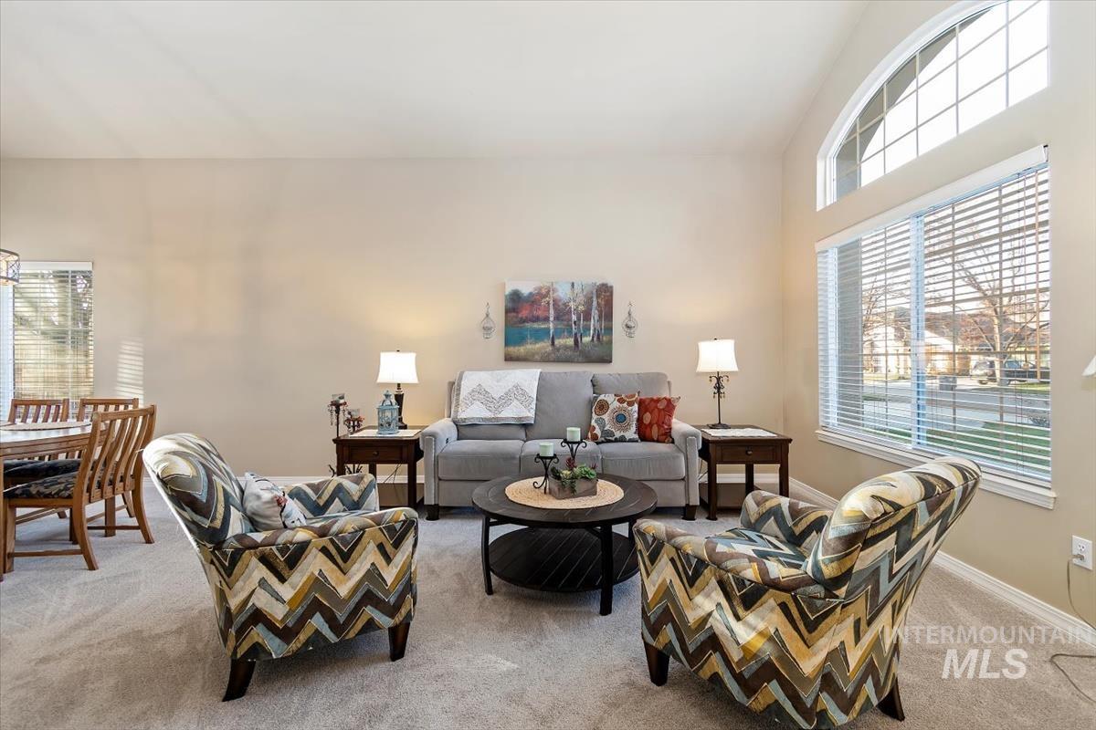 Living area with plenty of natural light, light carpet, and vaulted ceiling