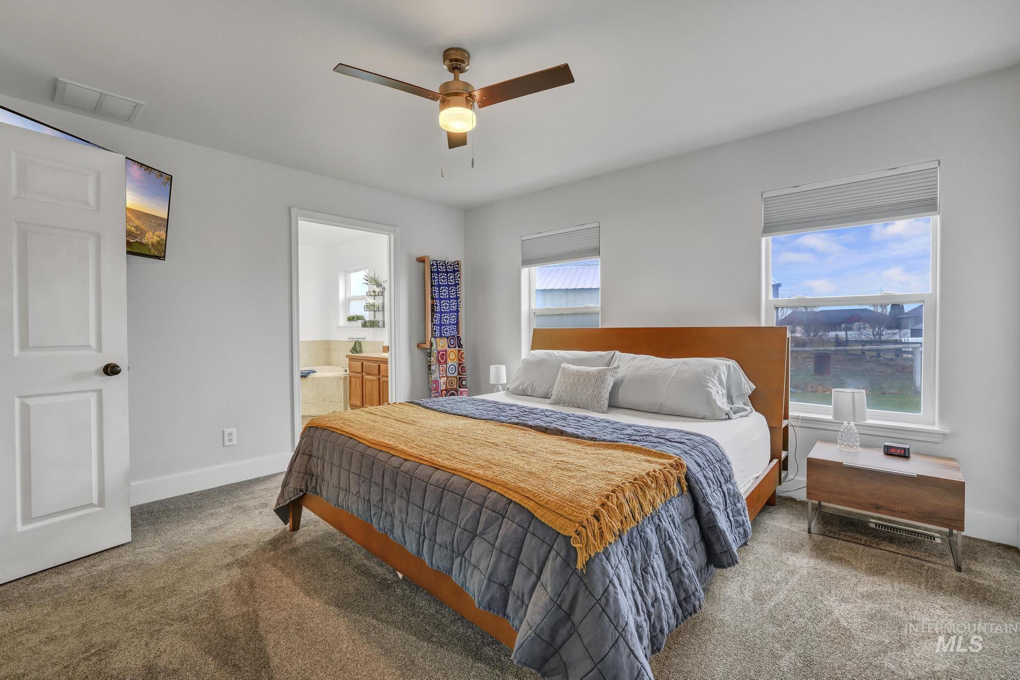 Bedroom with carpet flooring, ensuite bath, and ceiling fan