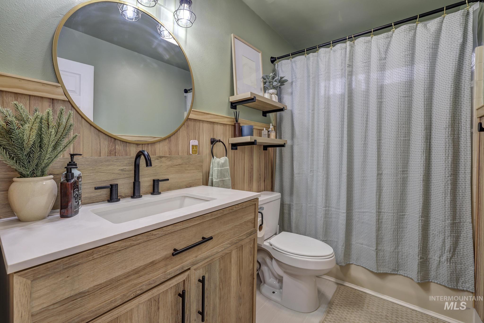 Bathroom featuring vanity, shower / bathtub combination with curtain, and light tile patterned floors