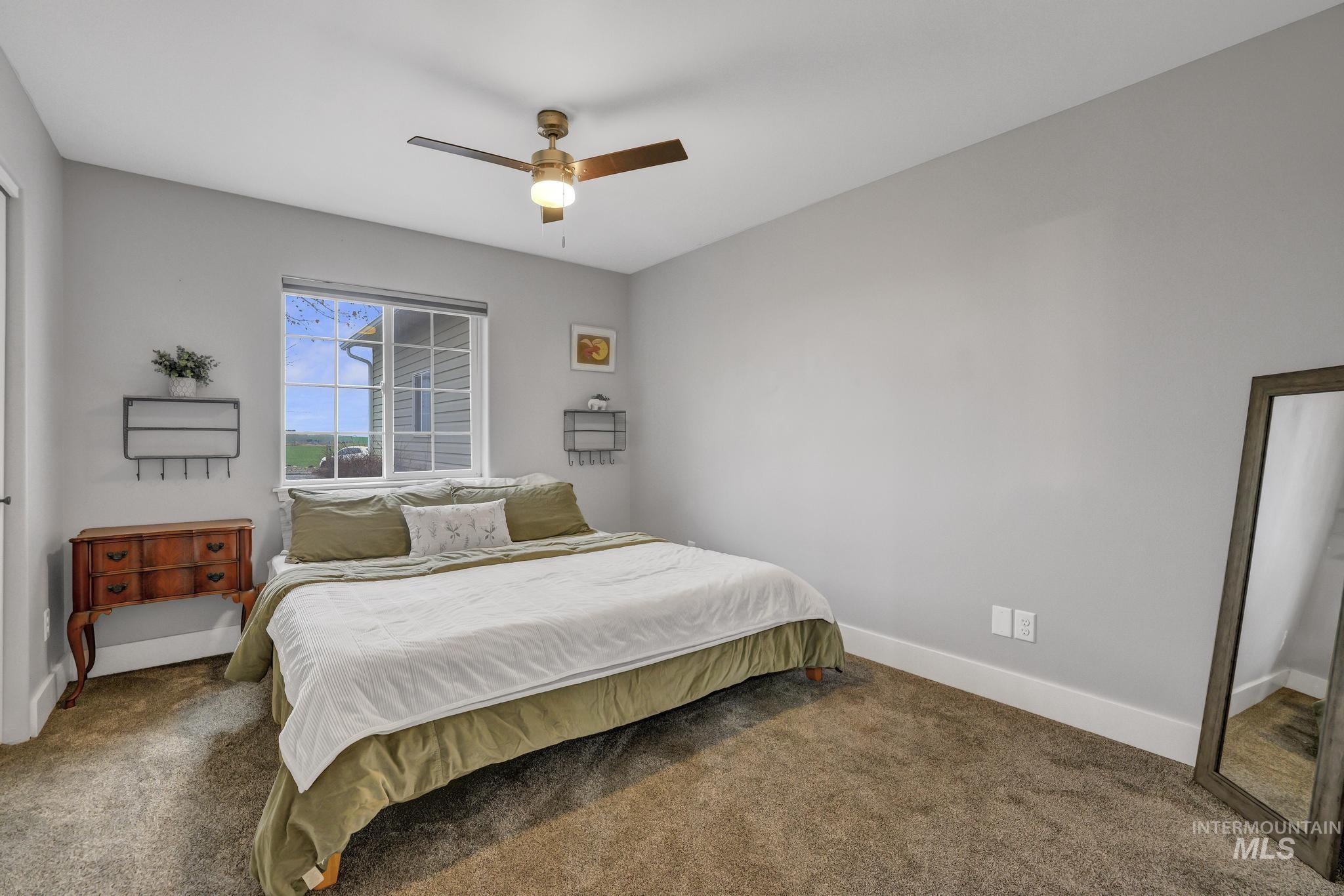 Carpeted bedroom featuring a ceiling fan and baseboards