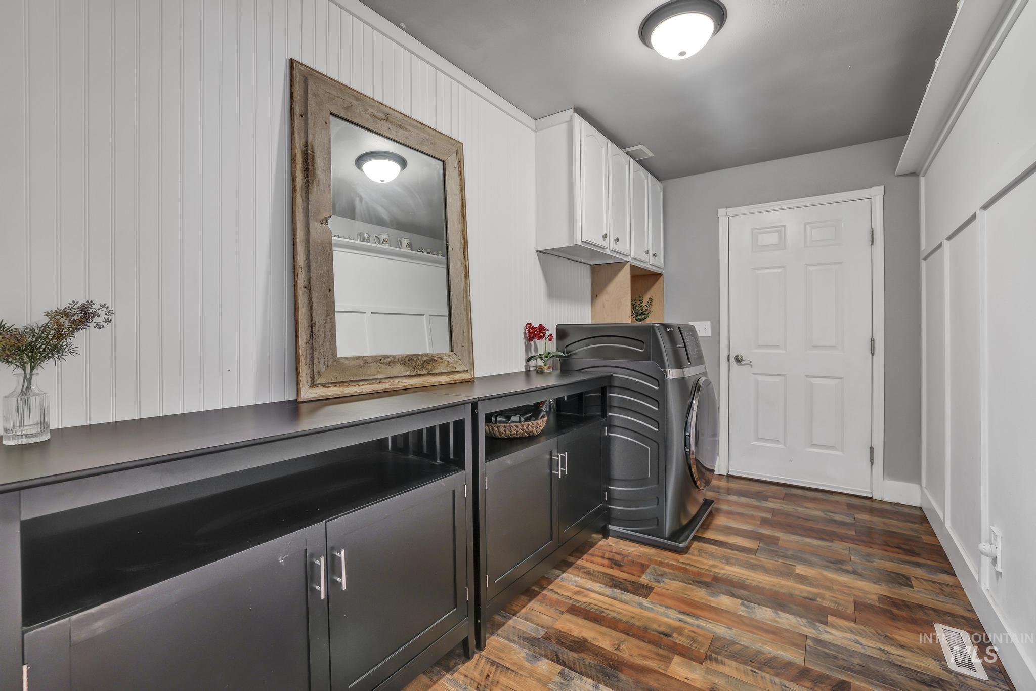 Laundry room featuring washer / dryer, dark wood-type flooring, and cabinet space