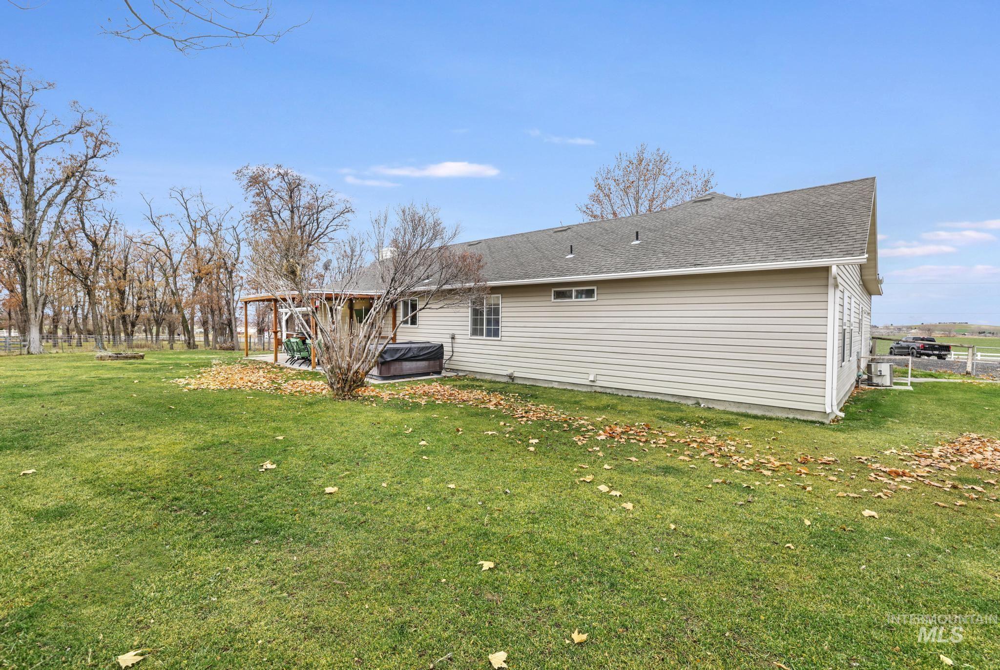 Rear view of house featuring a lawn, a hot tub, and roof with shingles