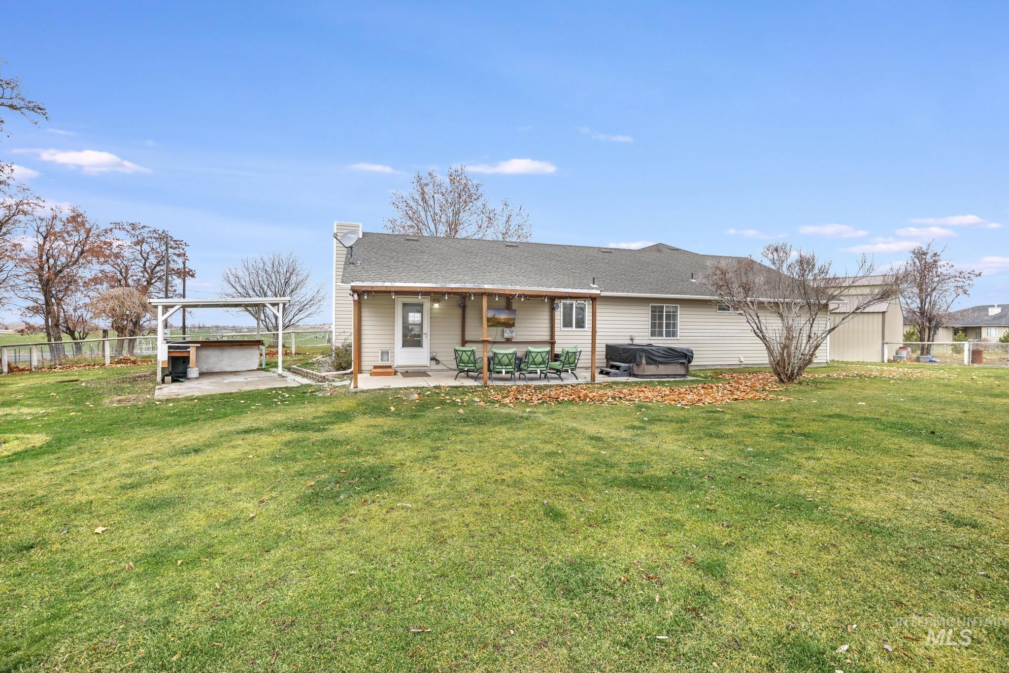 View of front of house featuring a hot tub, a patio, a chimney, roof with shingles, and a pergola