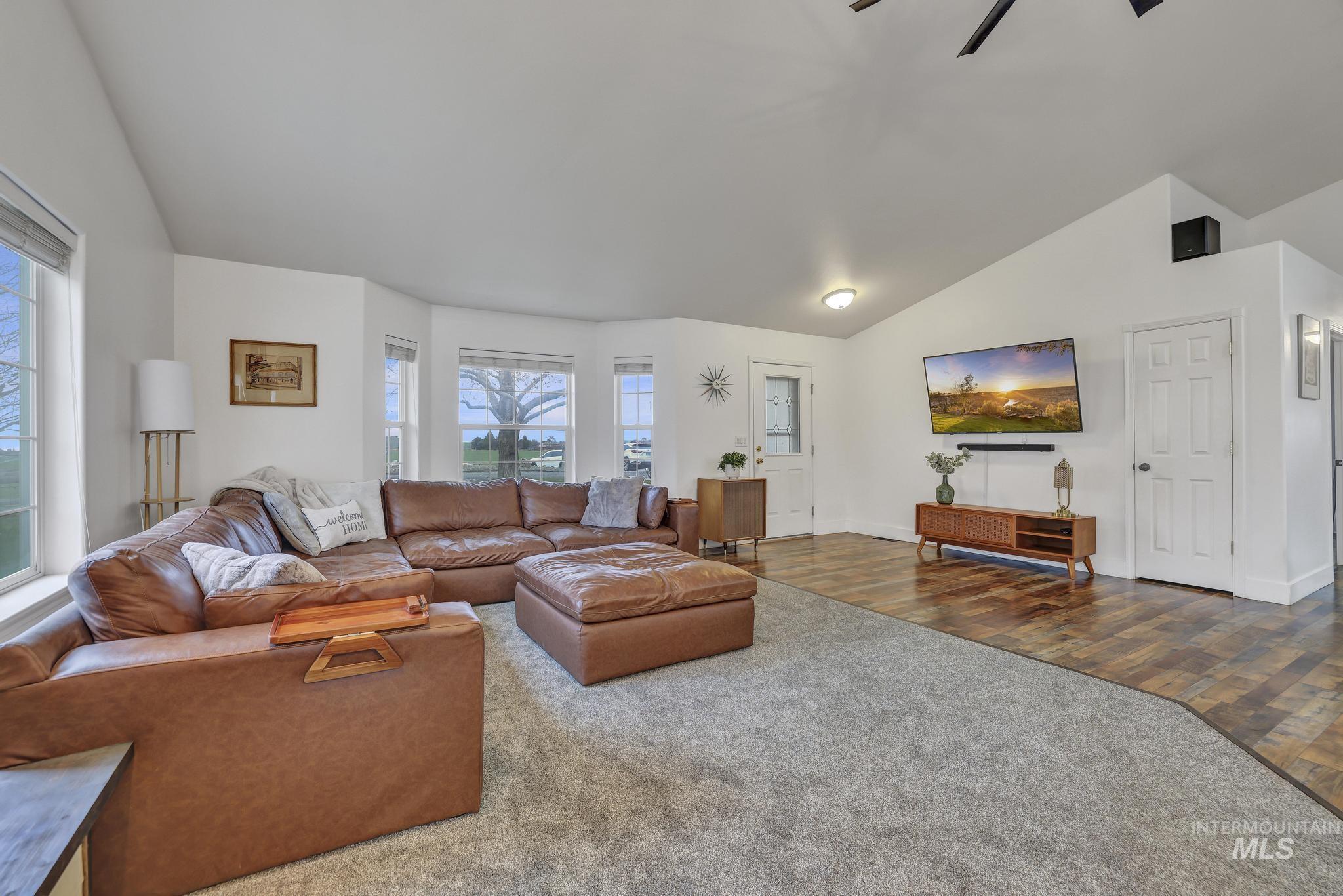 Living room featuring vaulted ceiling, a ceiling fan, and wood finished floors