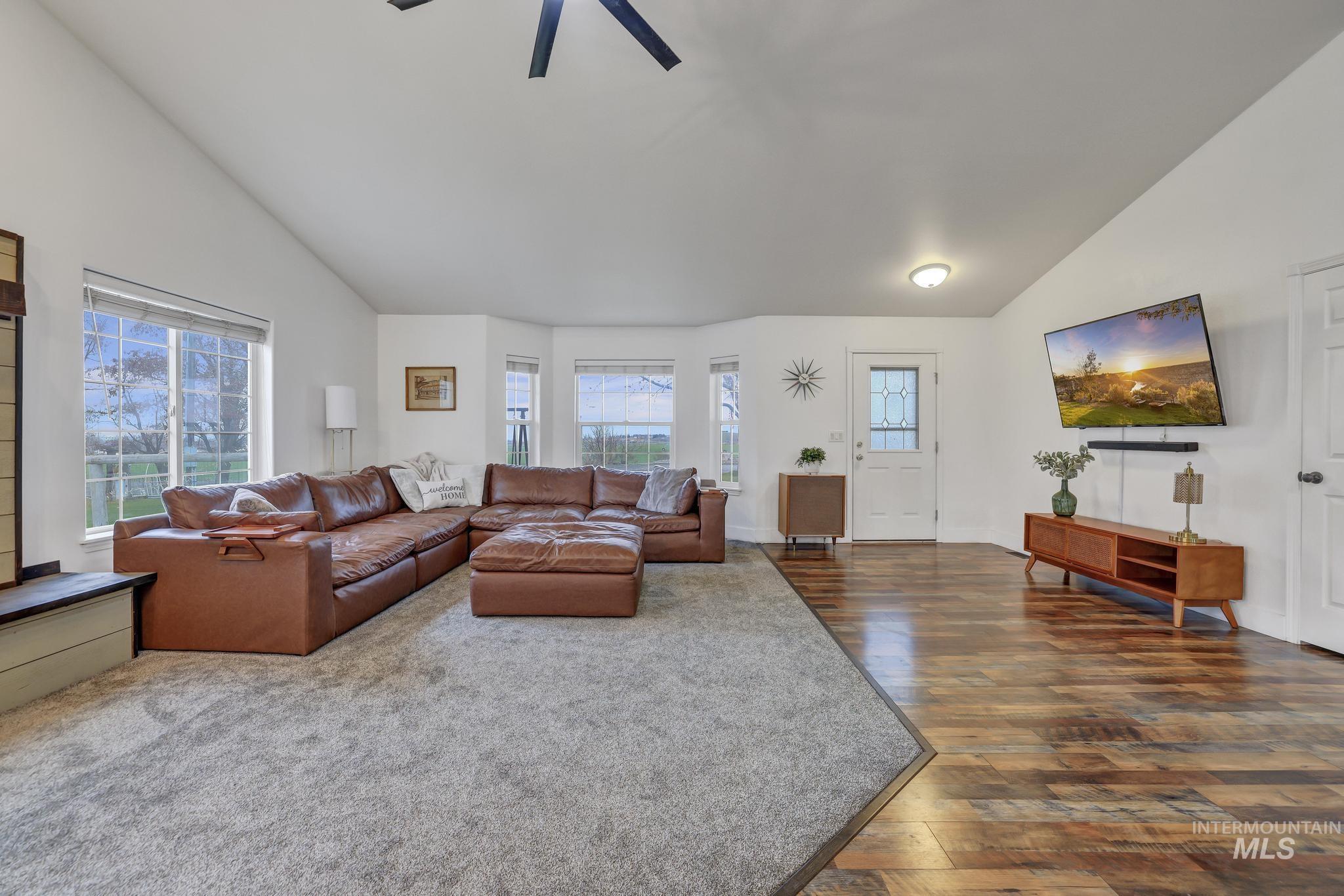 Living area featuring lofted ceiling, dark wood-style flooring, and ceiling fan
