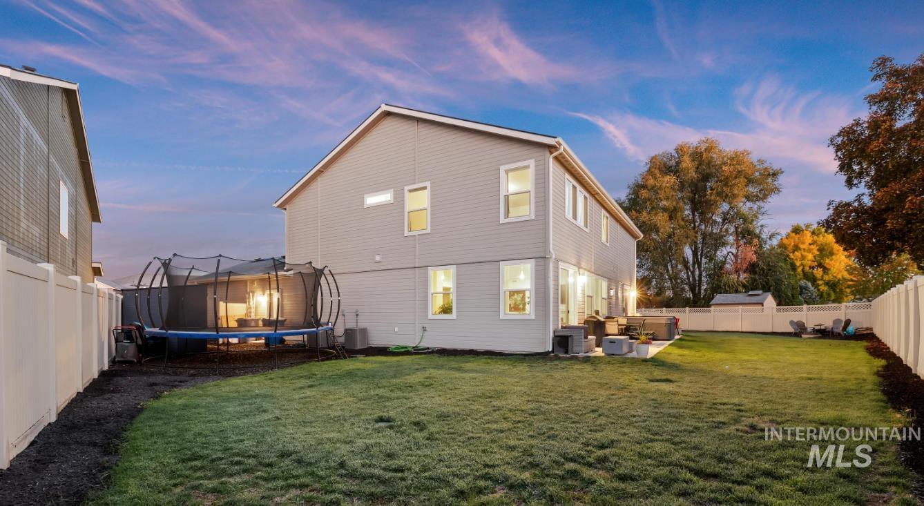 Rear view of house featuring a fenced backyard, a patio area, and a trampoline