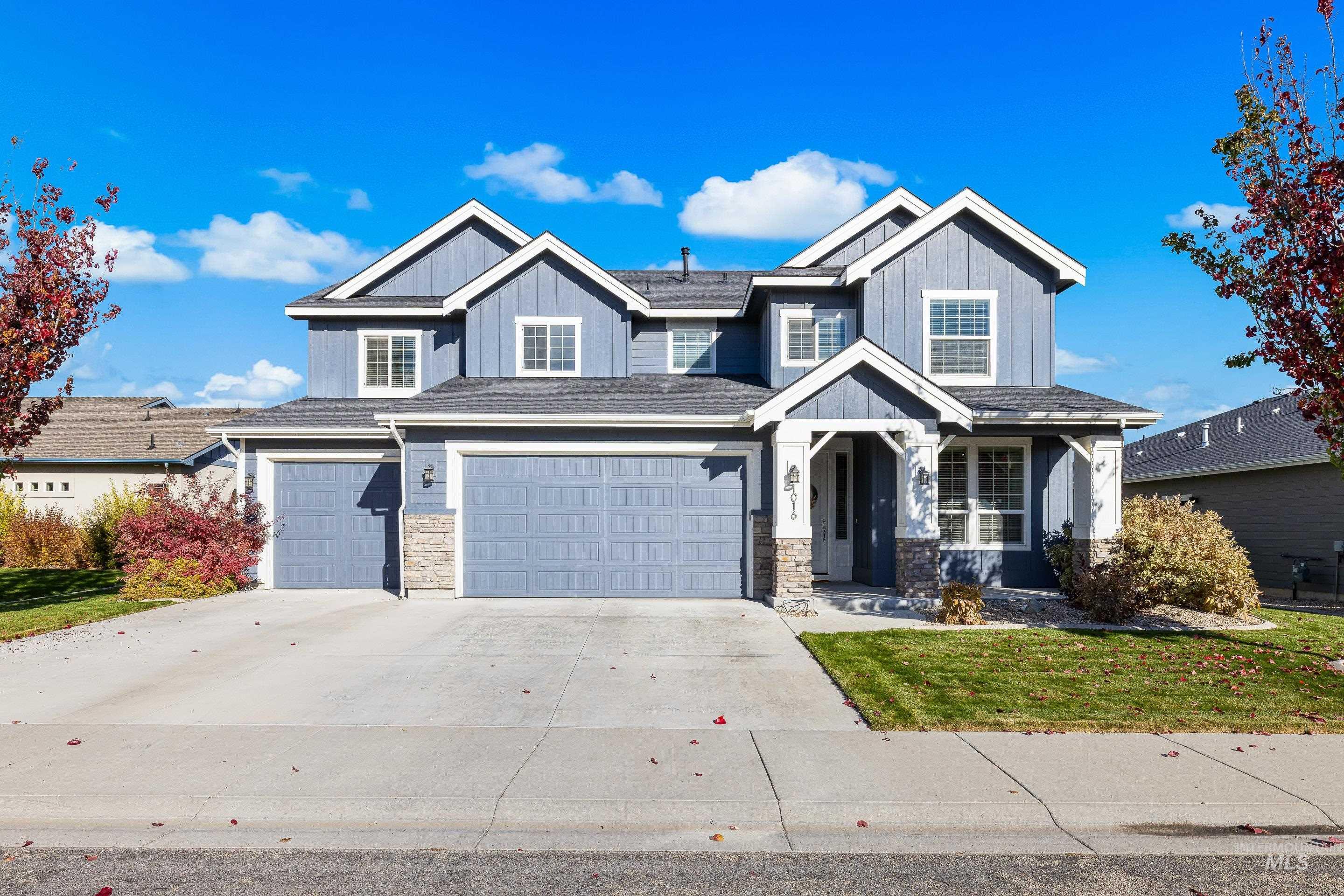 Craftsman house with stone siding, driveway, a garage, board and batten siding, and a front yard