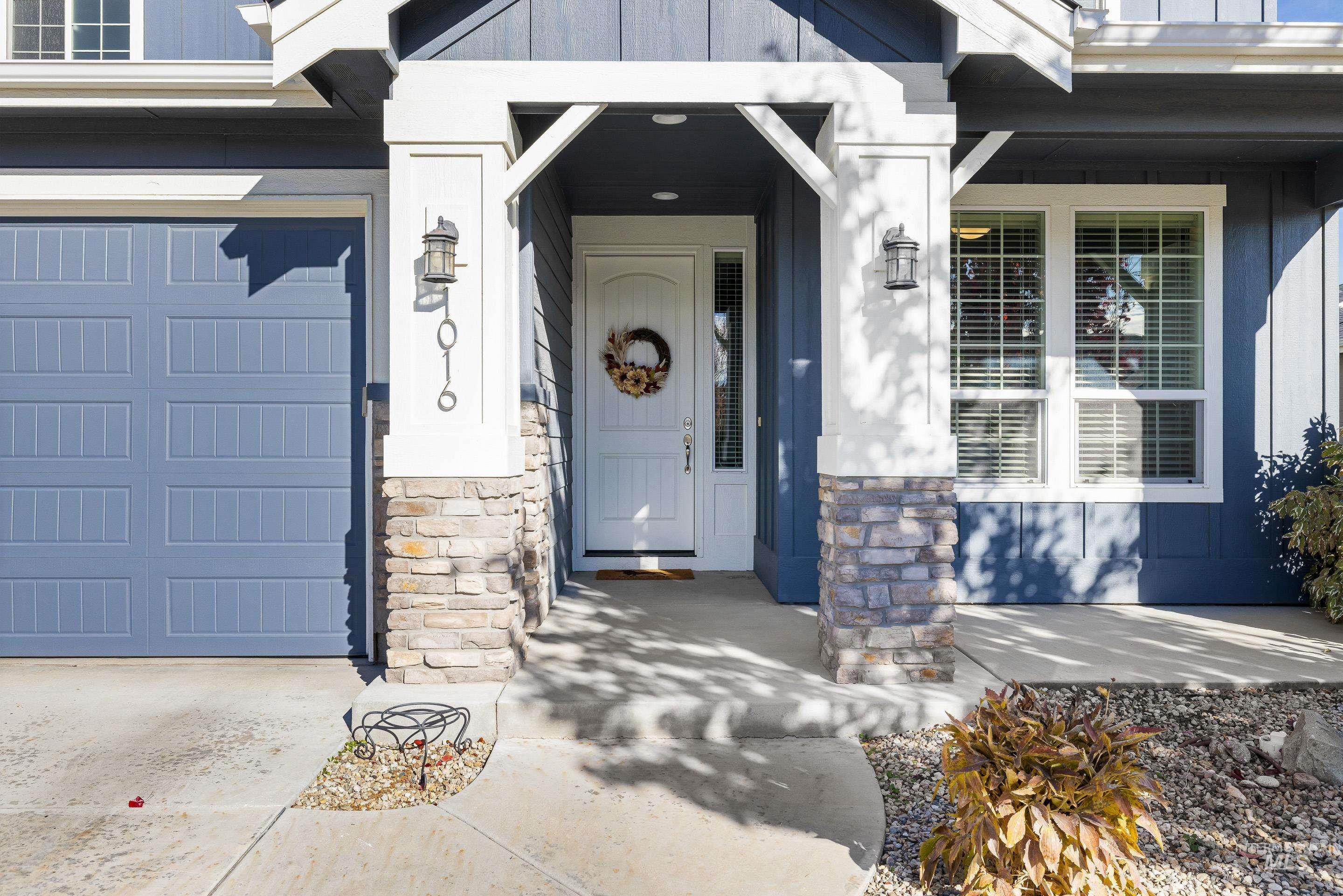 View of exterior entry featuring a garage, stone siding, and covered porch