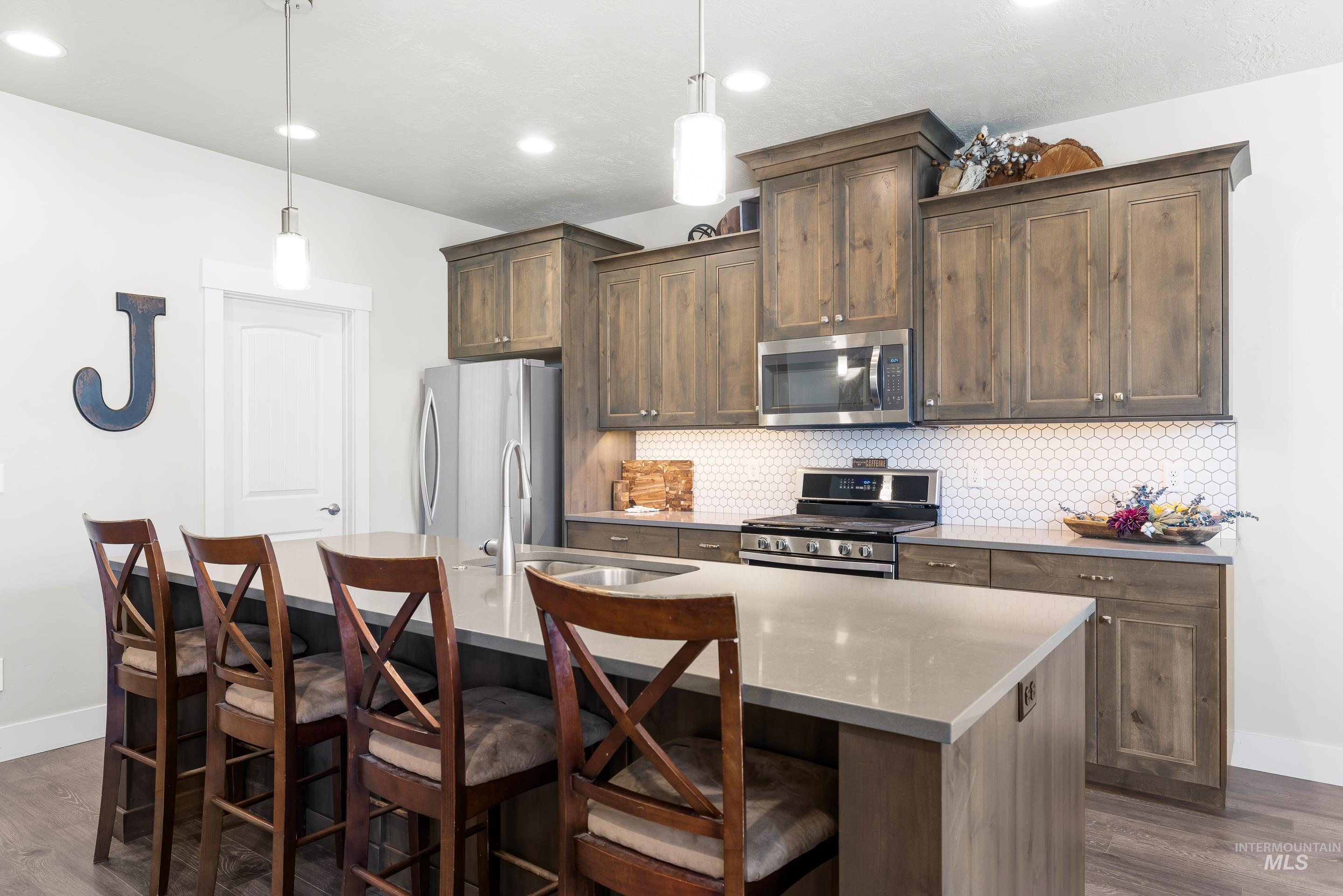 Kitchen featuring backsplash, dark wood-style flooring, and appliances with stainless steel finishes