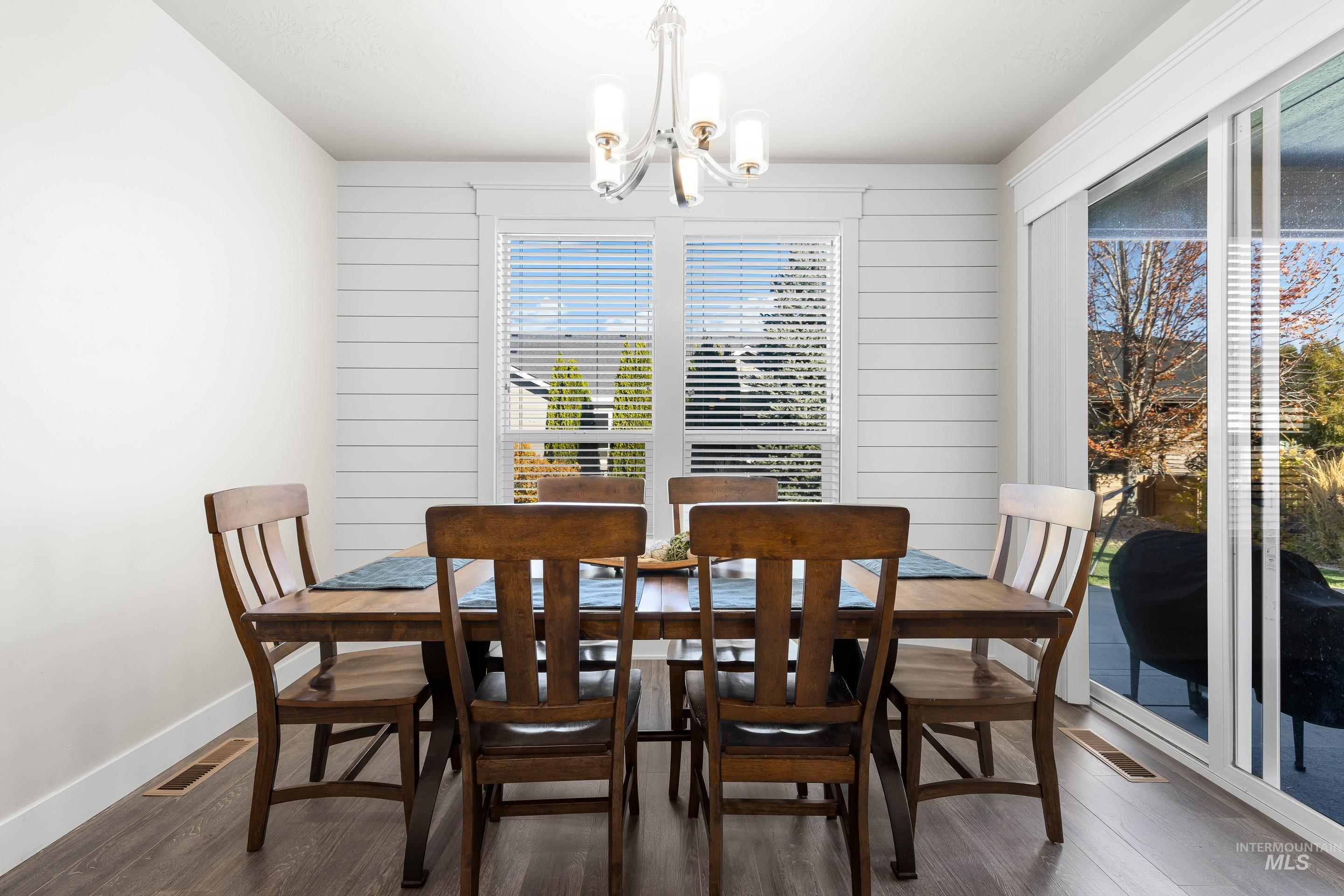 Dining area with dark wood-style floors, a chandelier, and wooden walls