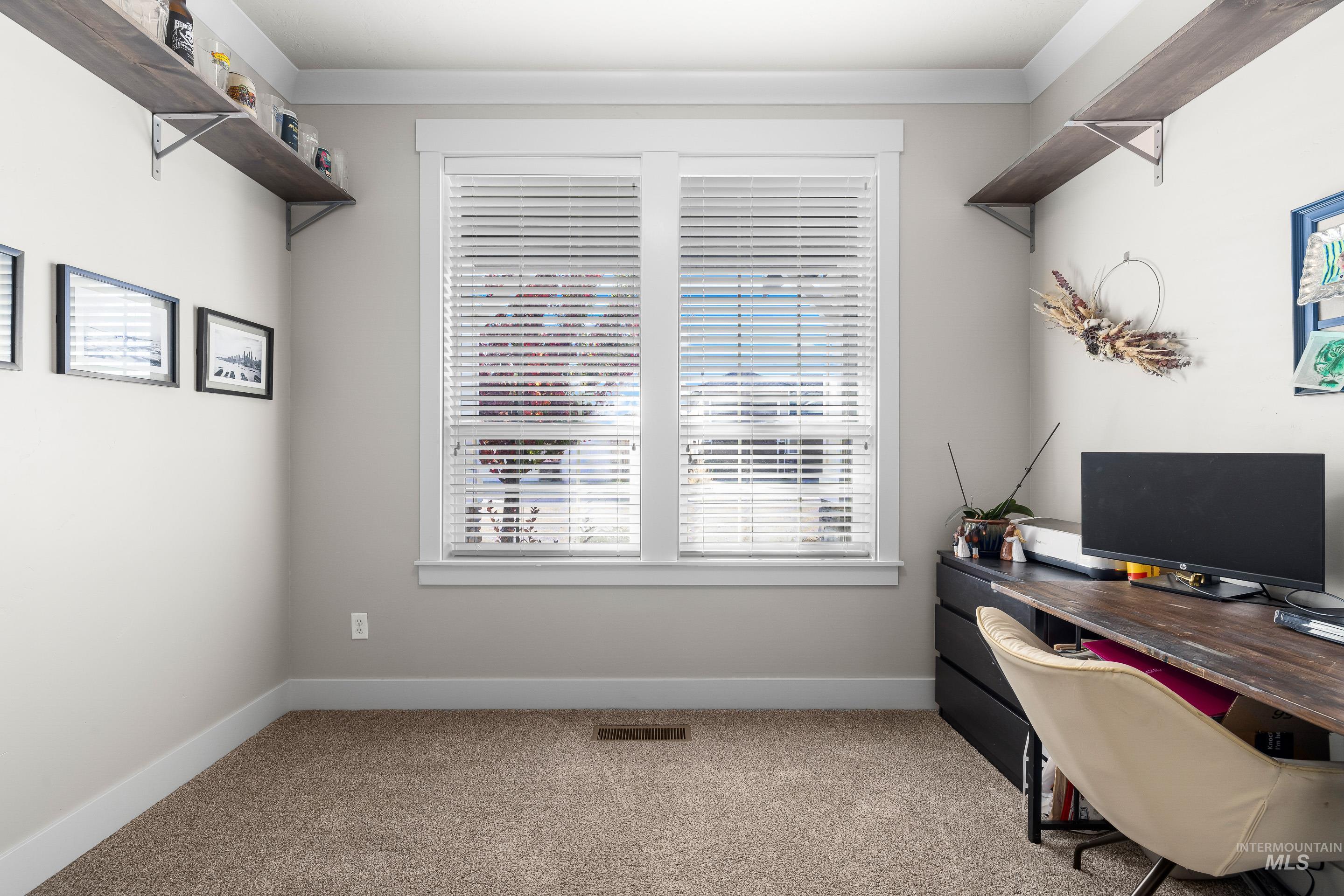 Home office with light colored carpet and baseboards