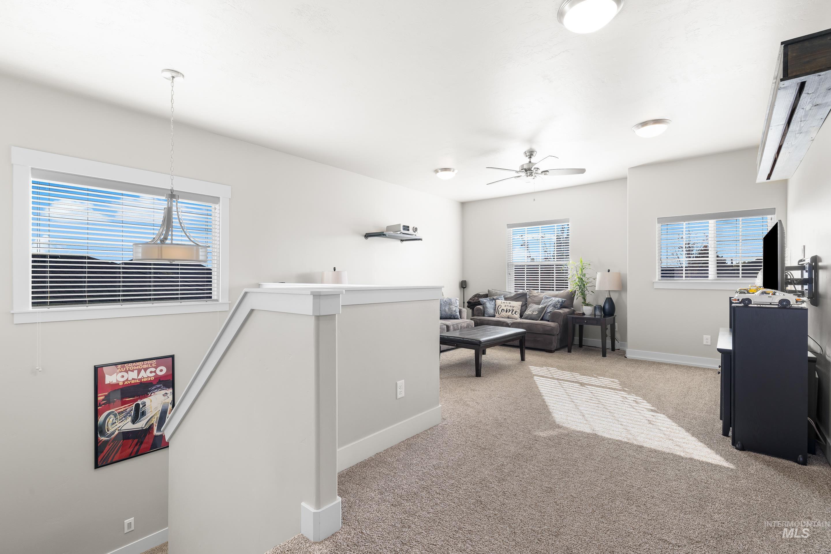 Living area featuring light colored carpet and ceiling fan