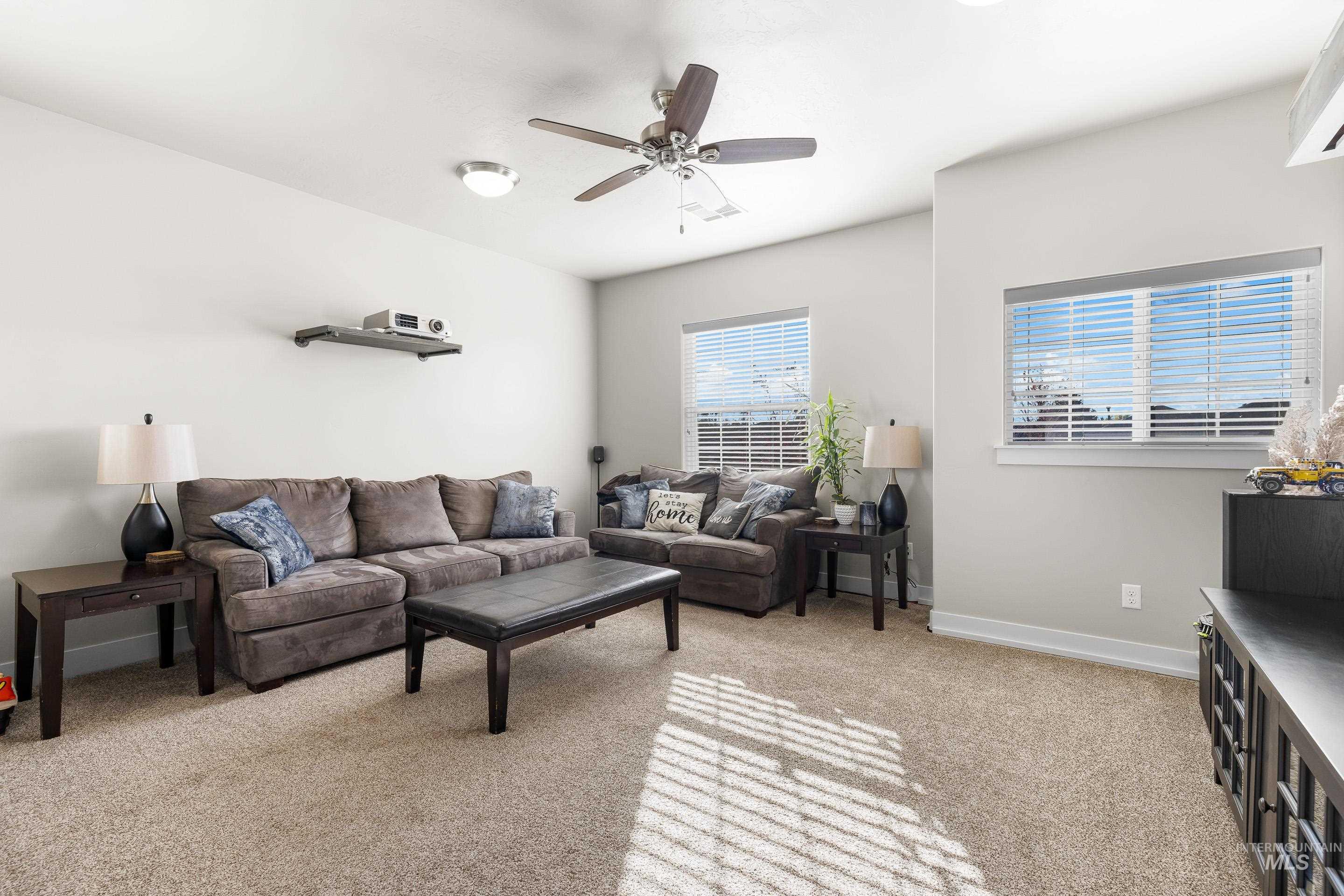 Living area featuring light carpet and ceiling fan