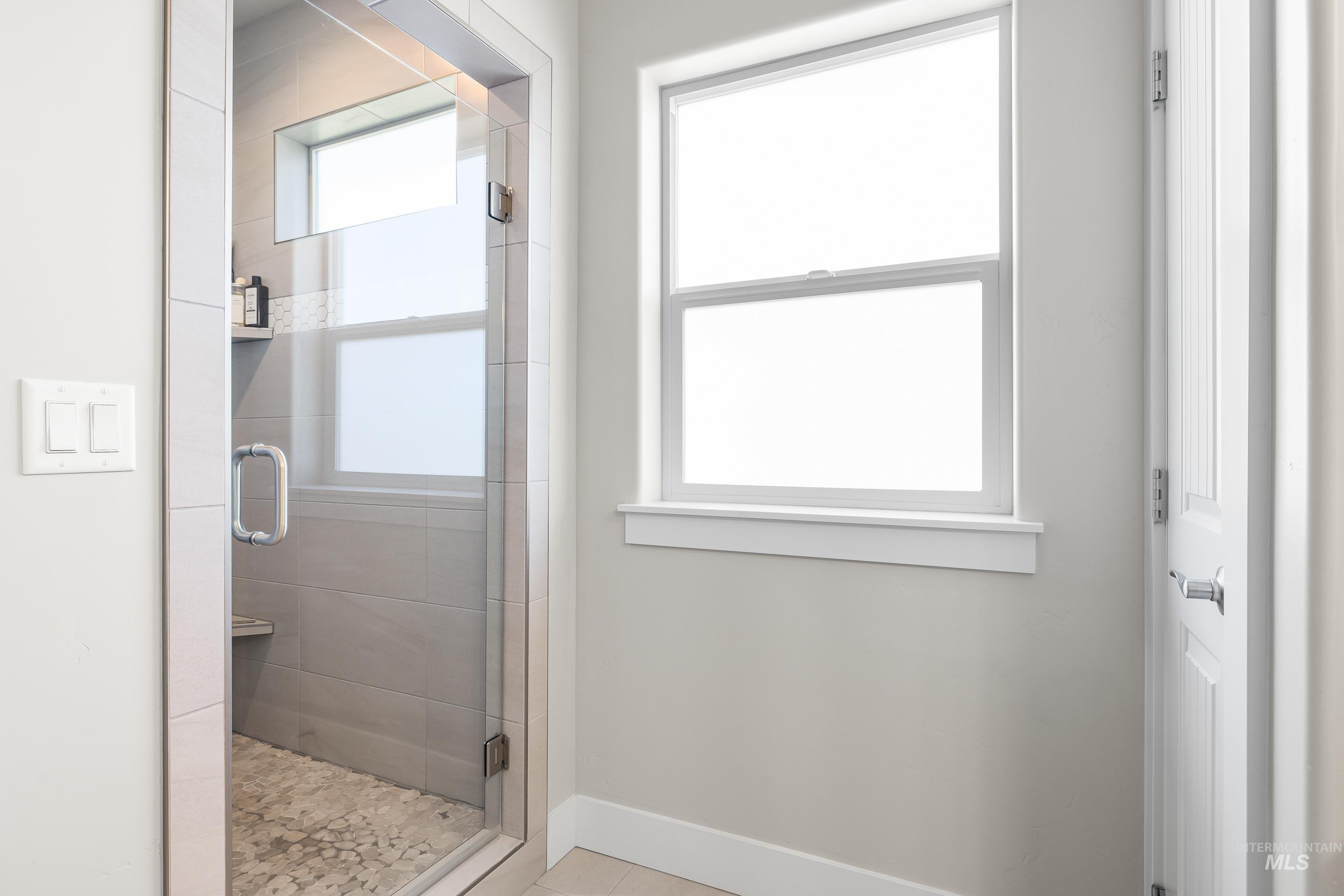 Full bathroom featuring a shower stall and light tile patterned floors