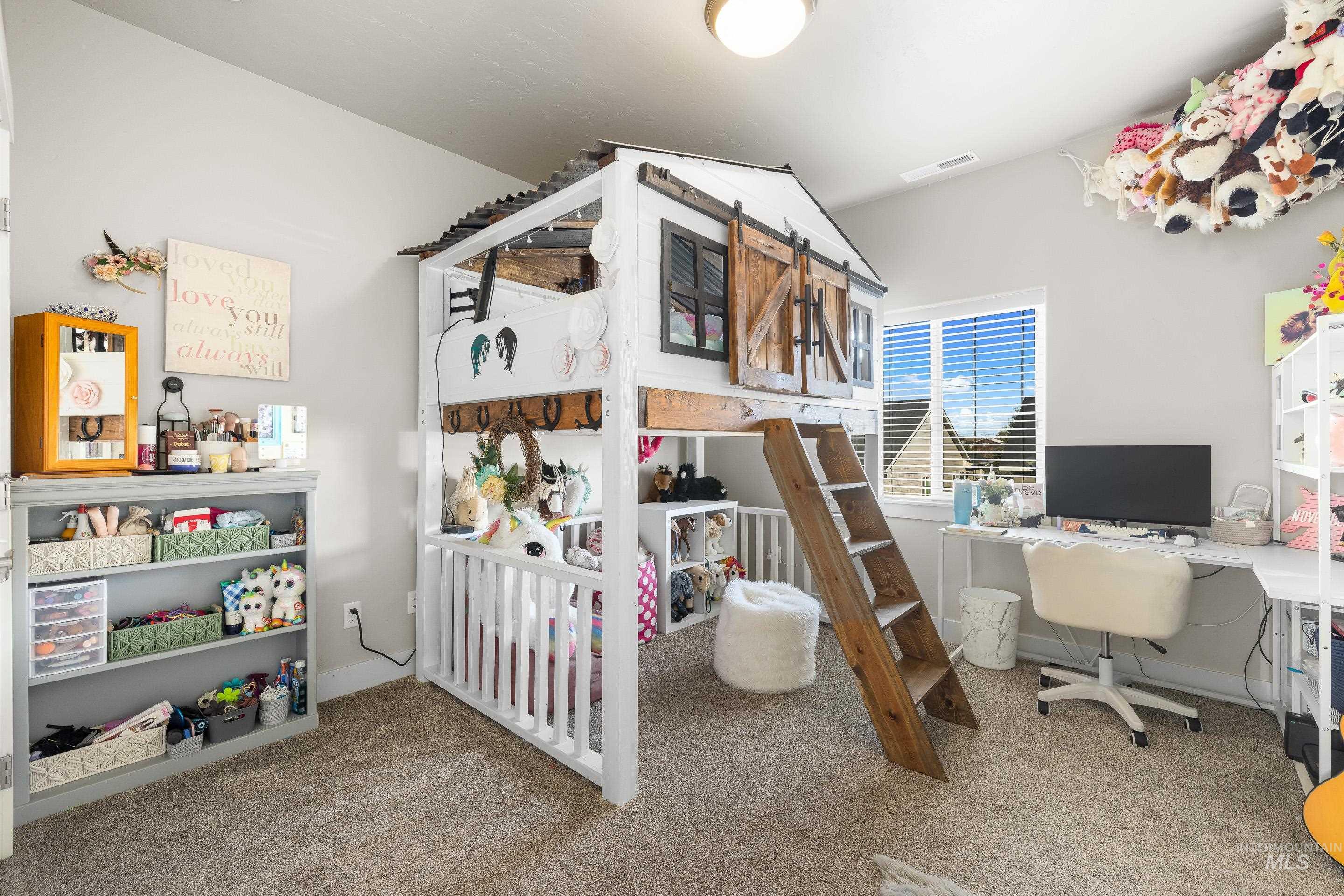 Bedroom with light colored carpet and a desk