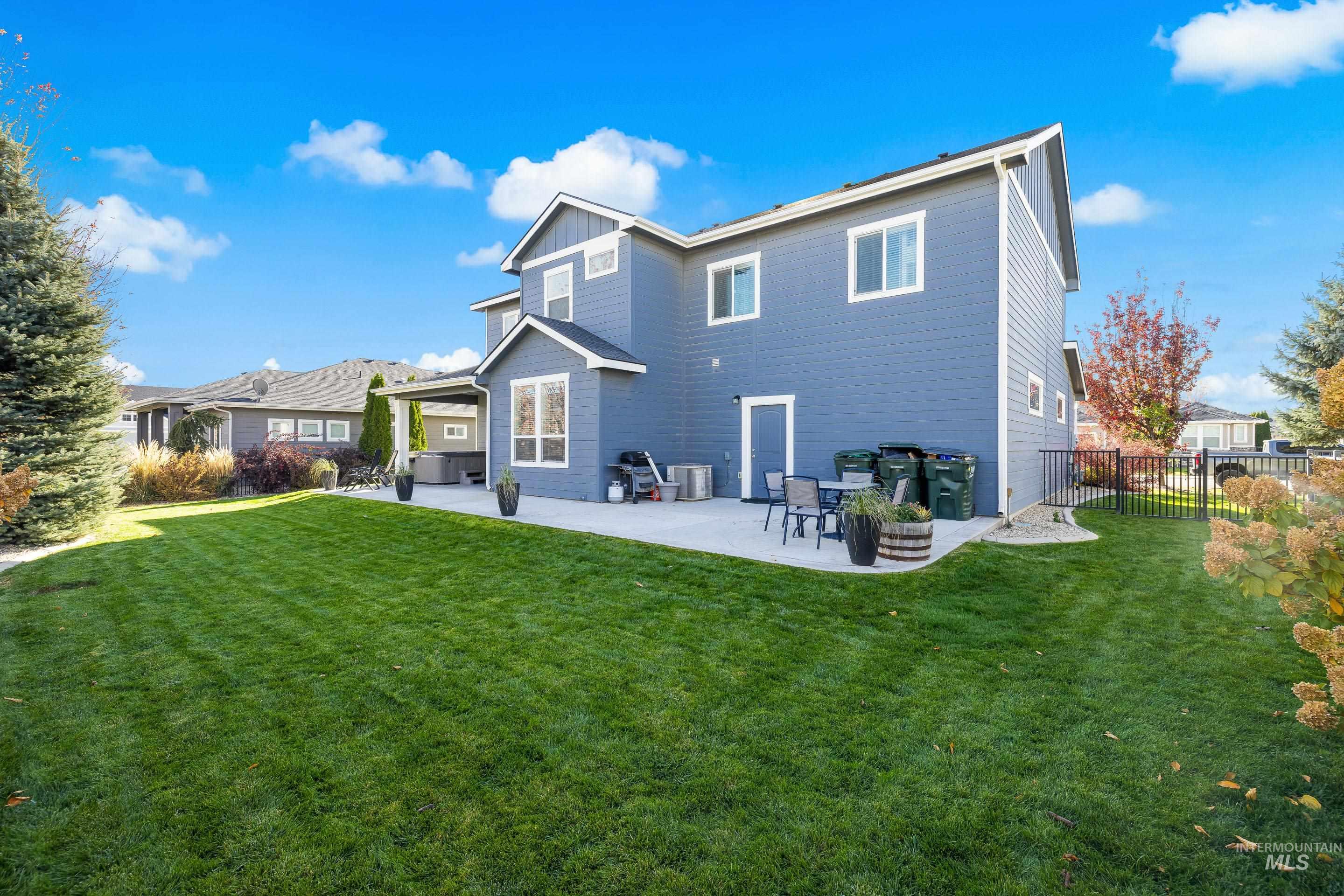 Rear view of house with a patio, a lawn, and board and batten siding