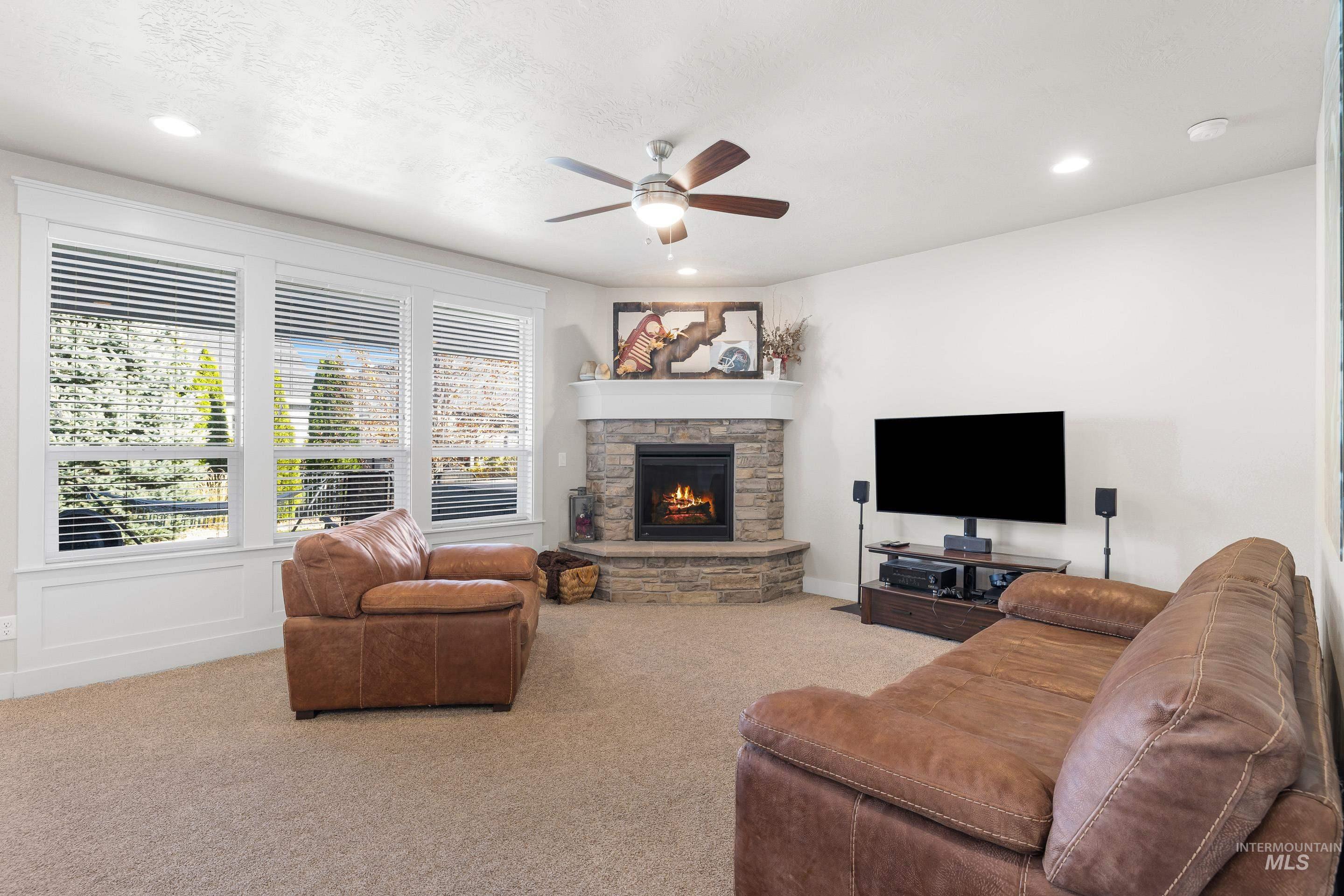 Living area with carpet flooring, ceiling fan, a fireplace, a decorative wall, and recessed lighting