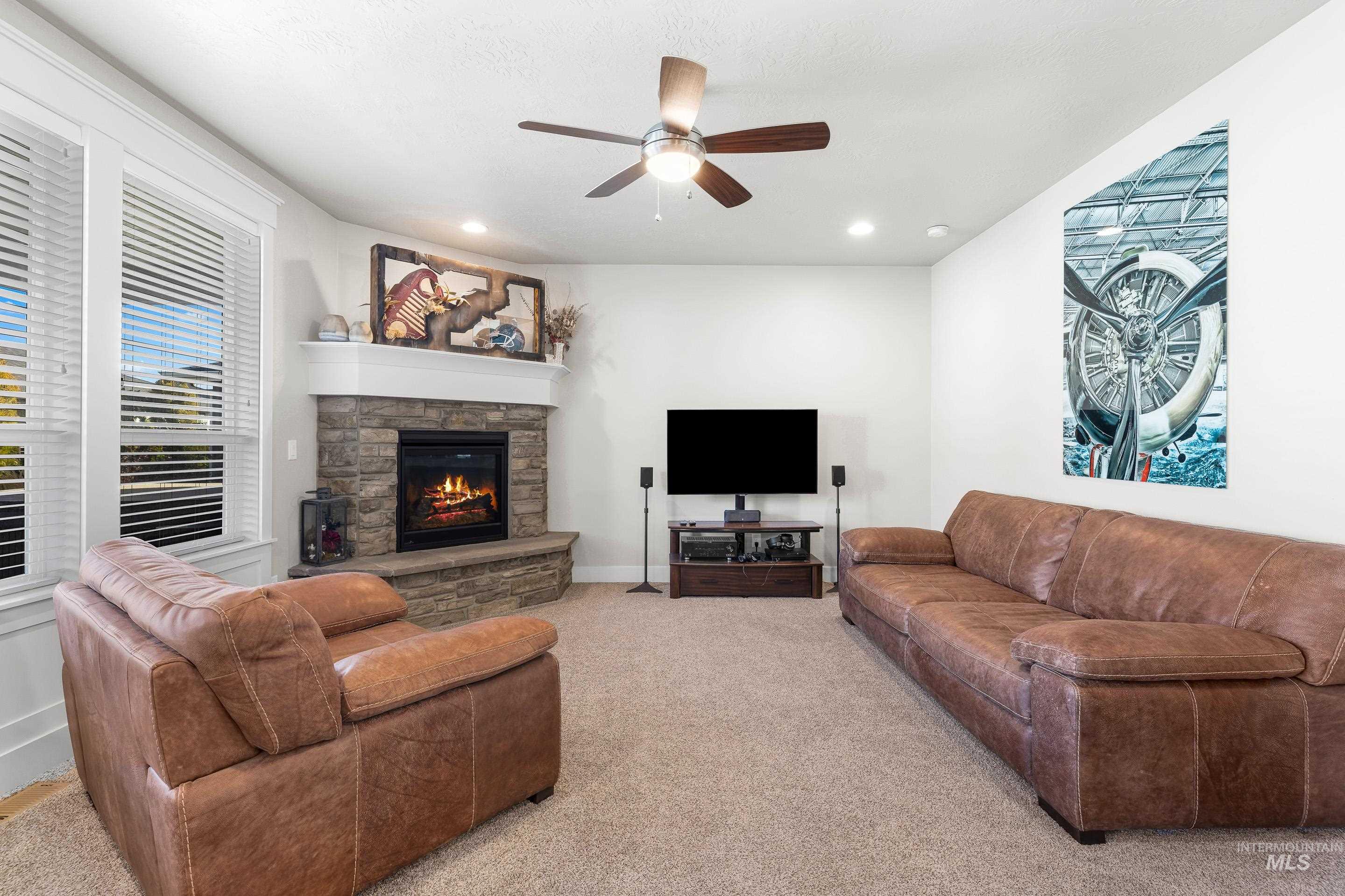 Carpeted living area featuring a fireplace, ceiling fan, and recessed lighting