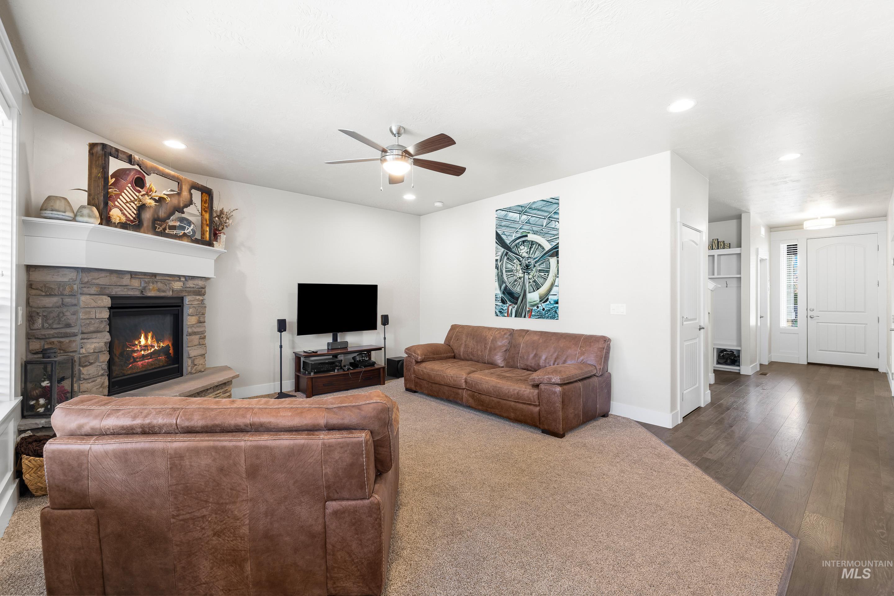 Living room featuring a fireplace, a ceiling fan, wood finished floors, and recessed lighting